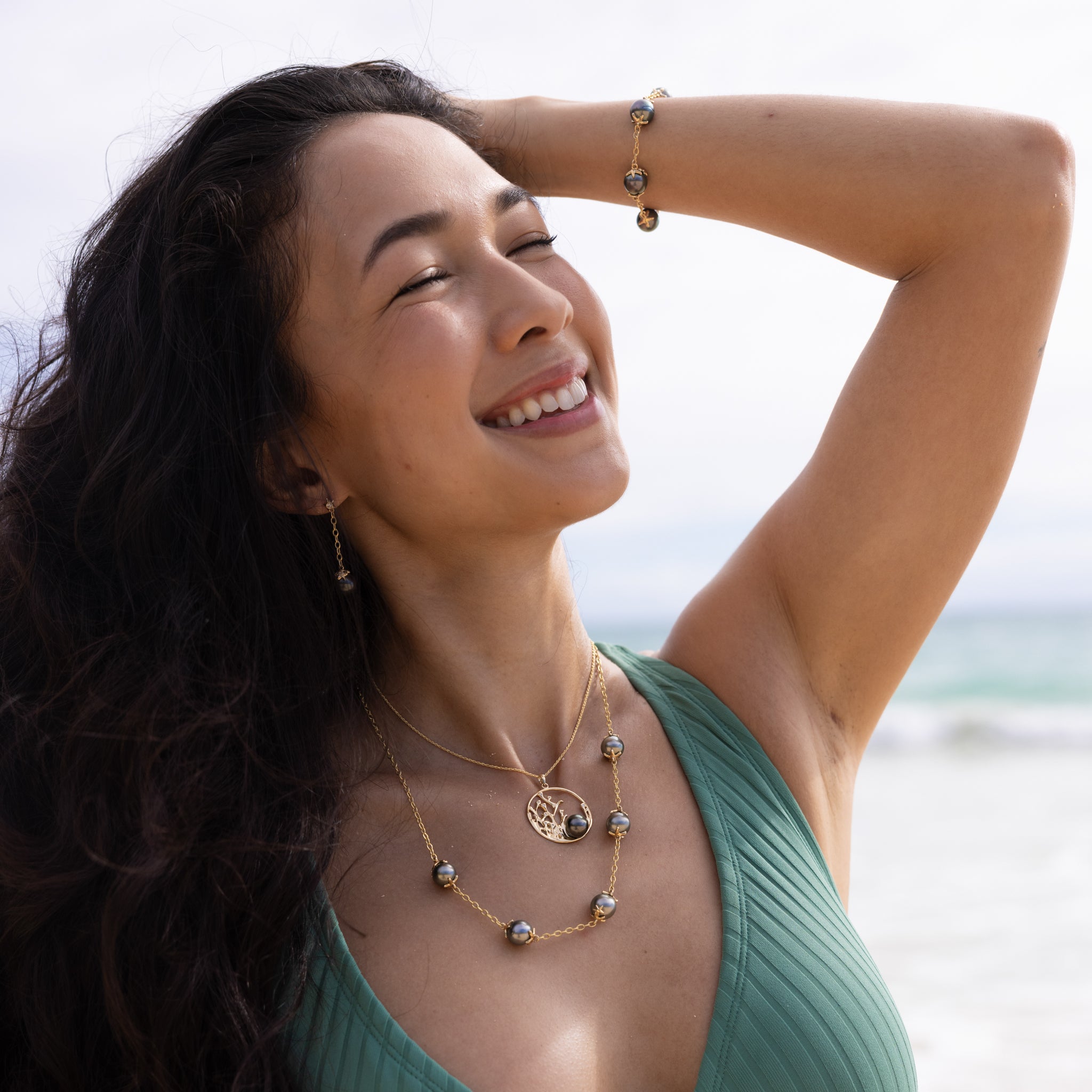 Woman on the beach wearing Reefs Tahitian Black Pearl Pendant, Earrings, Necklace and Bracelet in Gold