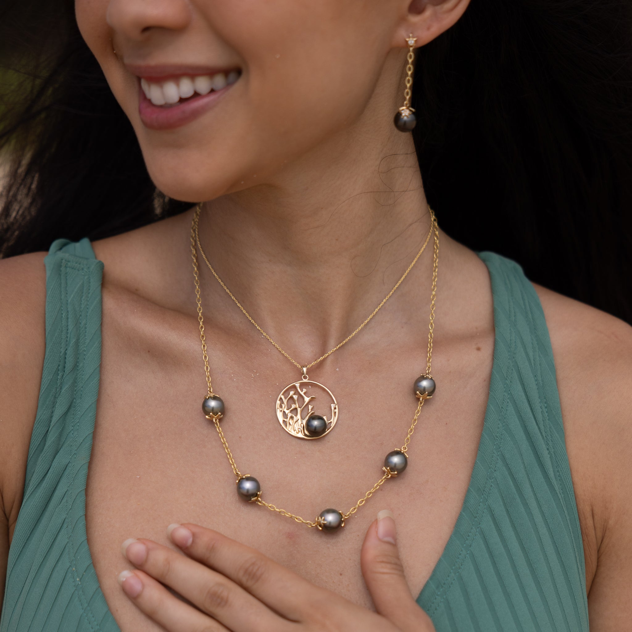 Close up of a woman wearing Reefs Tahitian Black Pearl Pendant, Earrings and Necklace in Gold with Diamonds