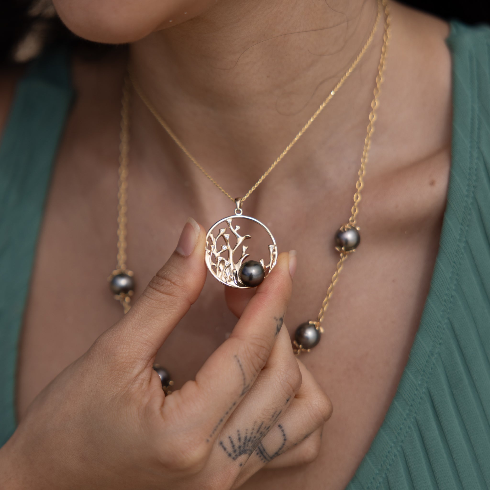 Close up of a 30mm Reefs Tahitian Black Pearl Pendant in Gold with Diamonds on a woman's neck