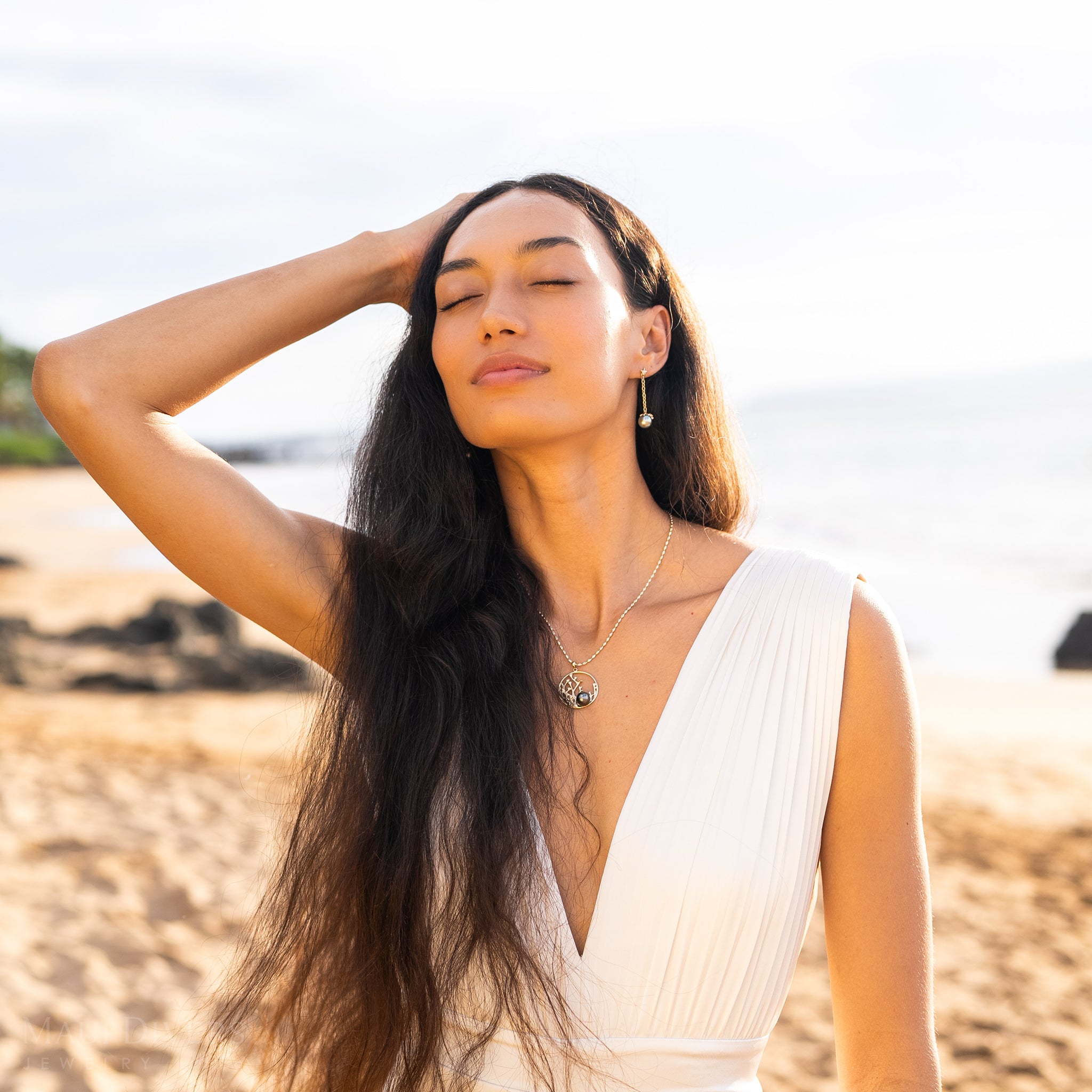 Woman on a beach wearing a 30mm Reefs Tahitian Black Pearl Pendant in Gold with Diamonds