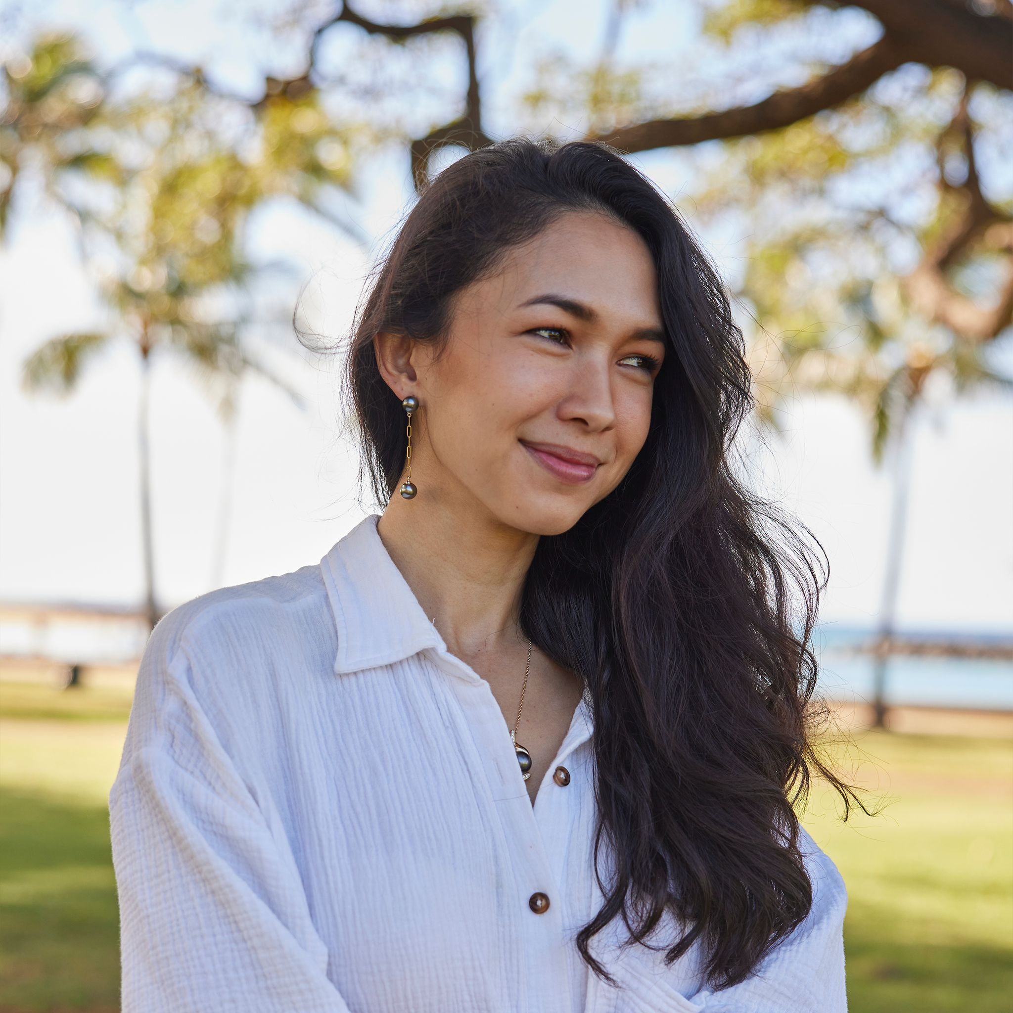 Woman at a beach park wearing 9-10mm Tahitian Black Pearl Paperclip Chain Earrings in 14k Yellow Gold