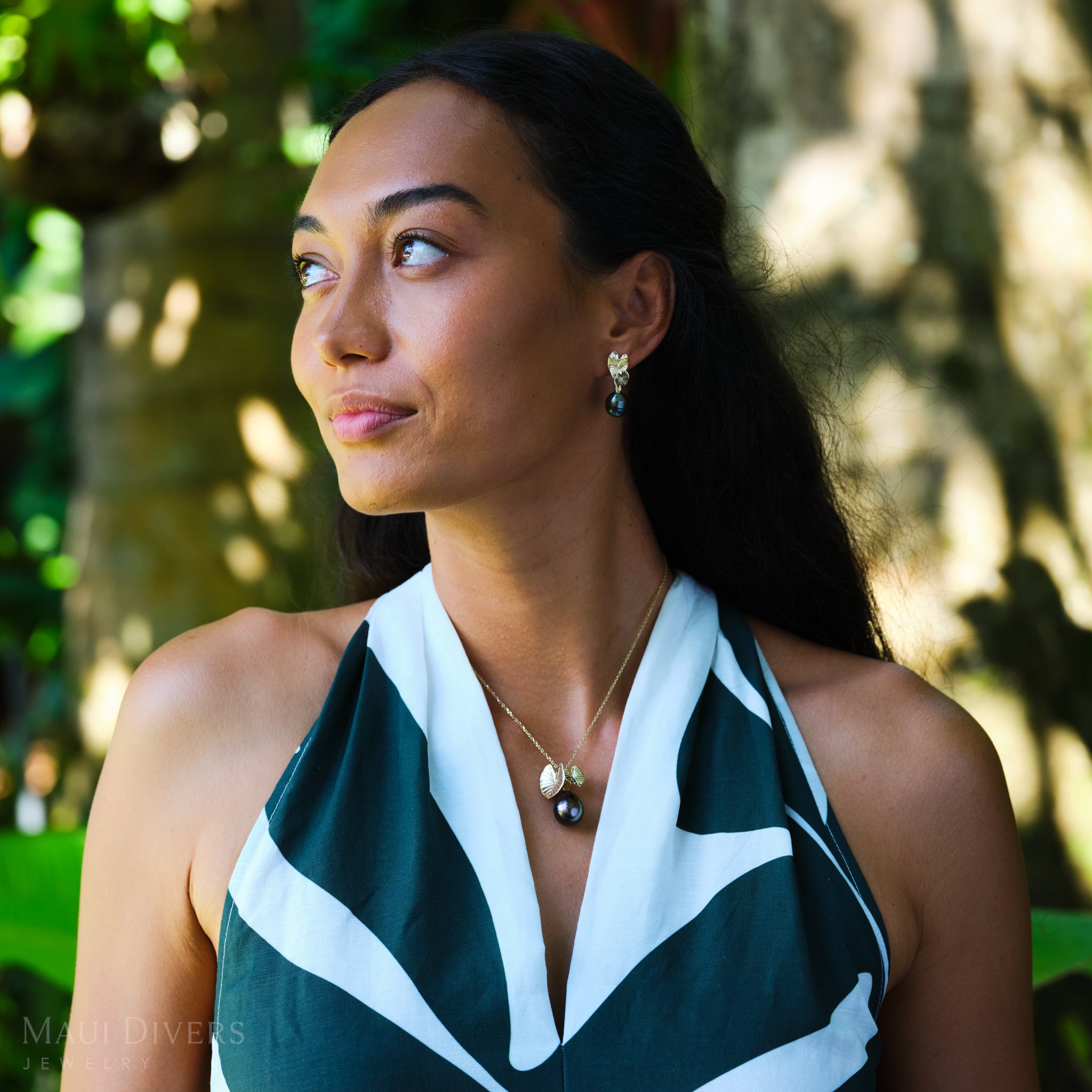 Woman in a garden wearing Kalo Circle Tahitian Black Pearl Pendant and Earrings in Gold