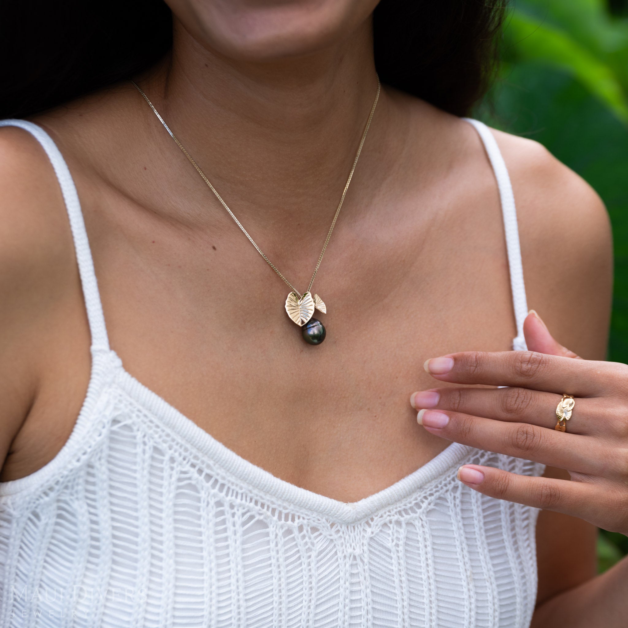 Woman wearing a Kalo 12-15mm Circle Tahitian Black Pearl Pendant in Gold with blurred green background