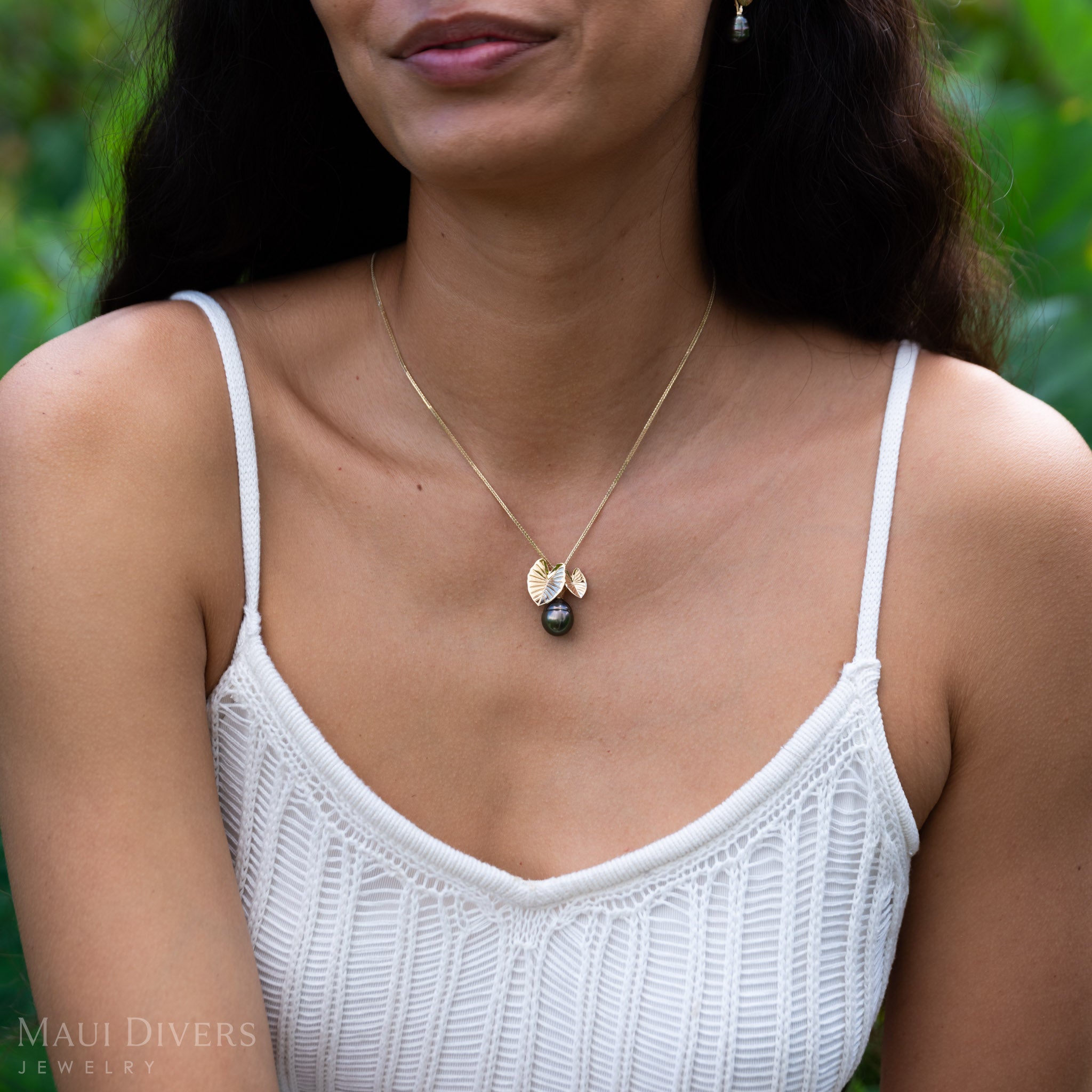 Woman wearing a Kalo 12-15mm Circle Tahitian Black Pearl Pendant in Gold with blurred green background