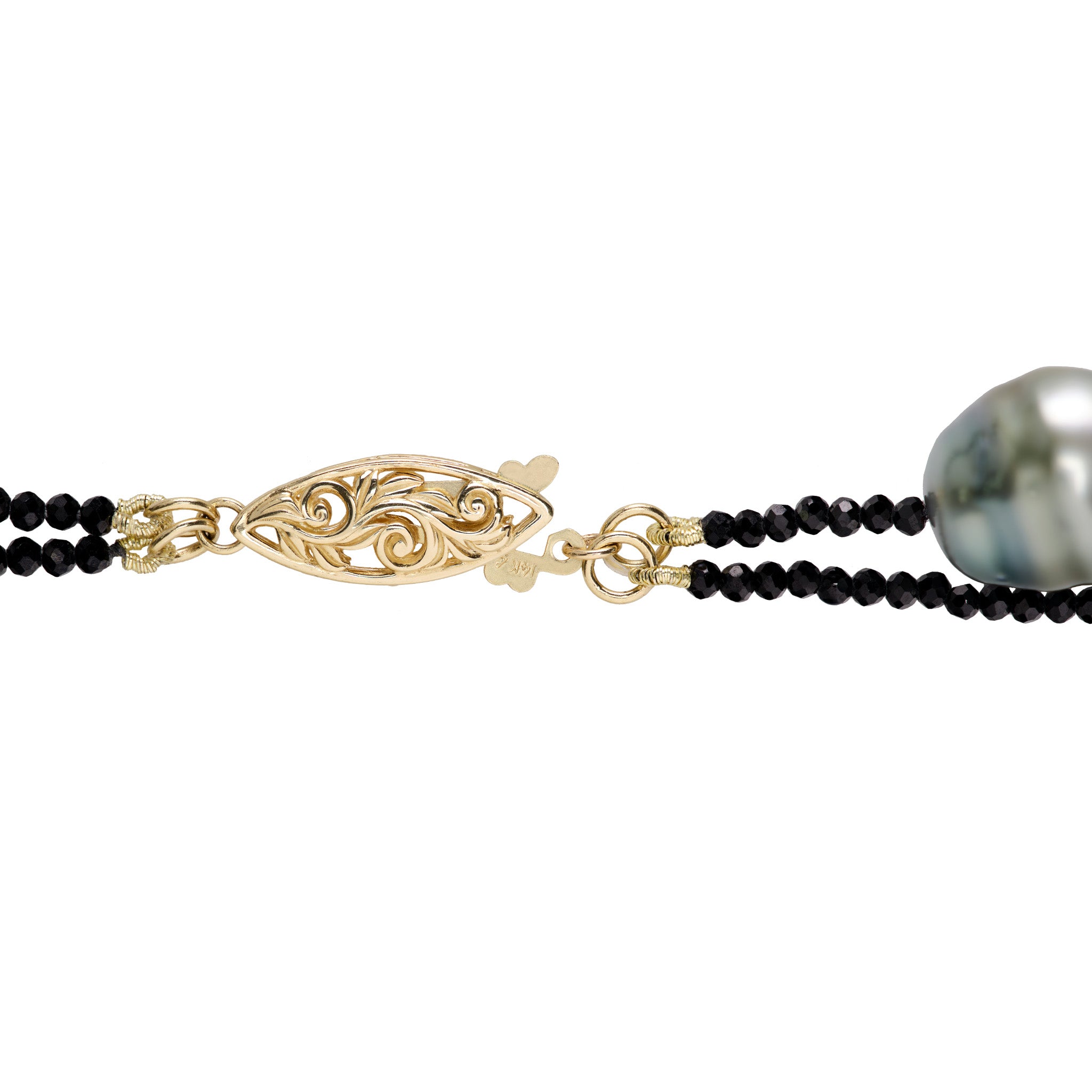 Detail shot of the Living Heirloom football clasp in 14k yellow gold with the black spinel and Tahitian pearl necklace on a white background