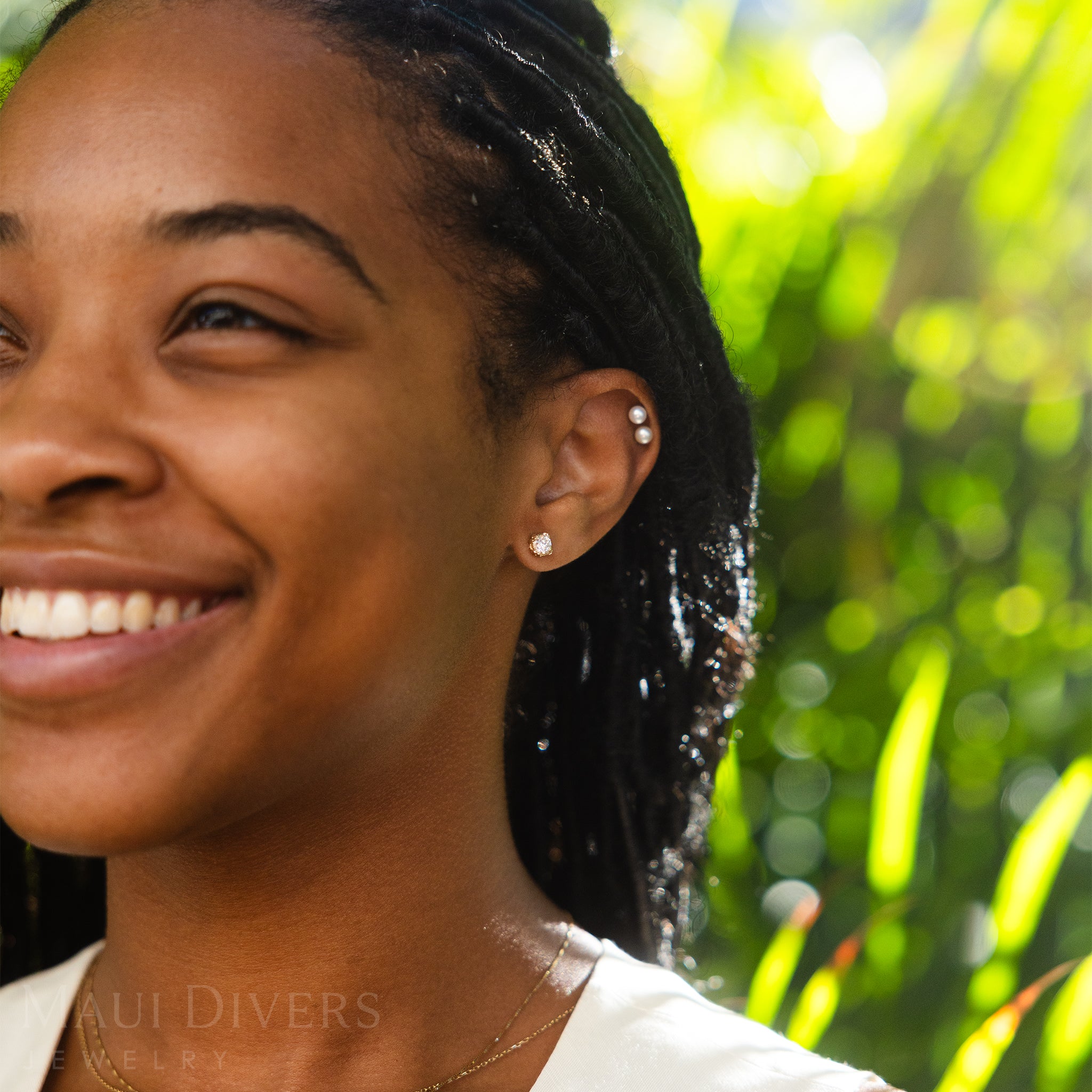 Woman with a smile outdoors wearing Hidden Hawaiʻi Maile Earrings in Gold with Lab Grown Diamonds
