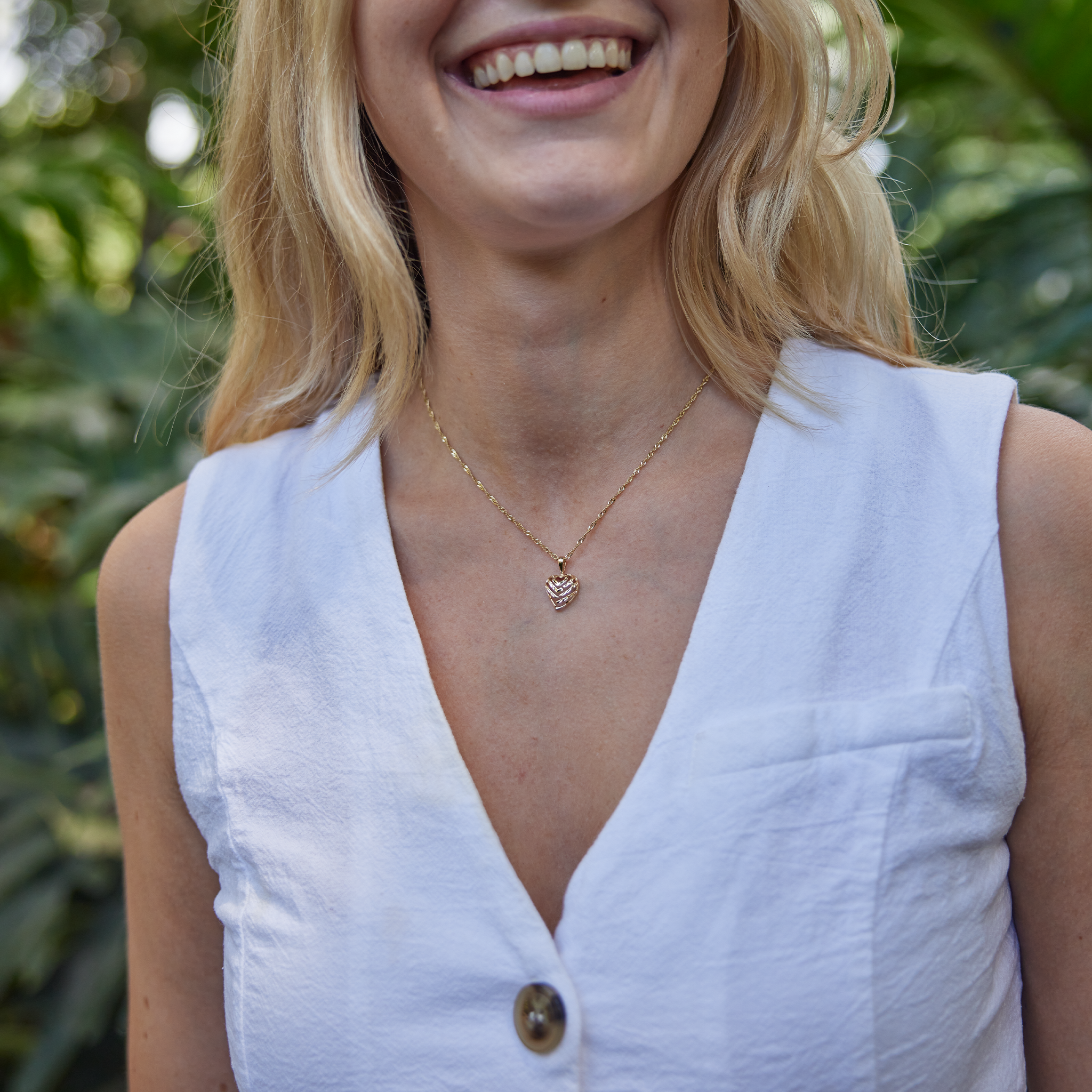 woman in white wearing Aloha Heart Pendant in Gold - 12mm with nature background