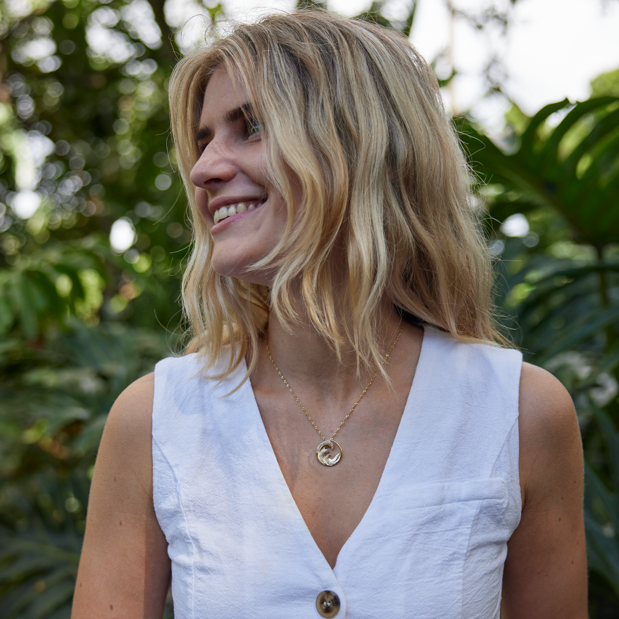 Woman in white shirt wearing Nalu wave Pendant in Gold with Diamonds