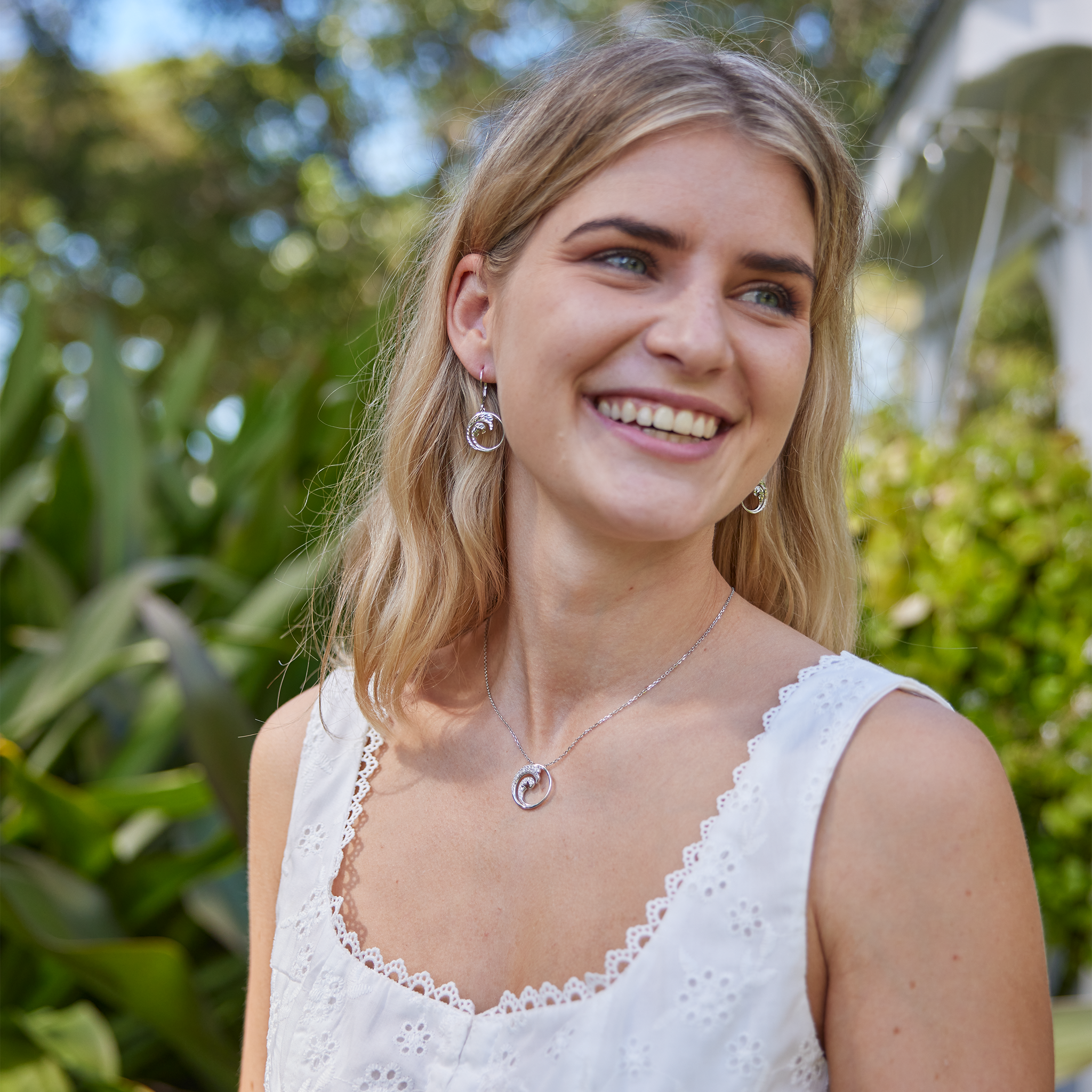 Woman wearing Nalu Pendant in White Gold with Diamonds - 22mm with nature background
