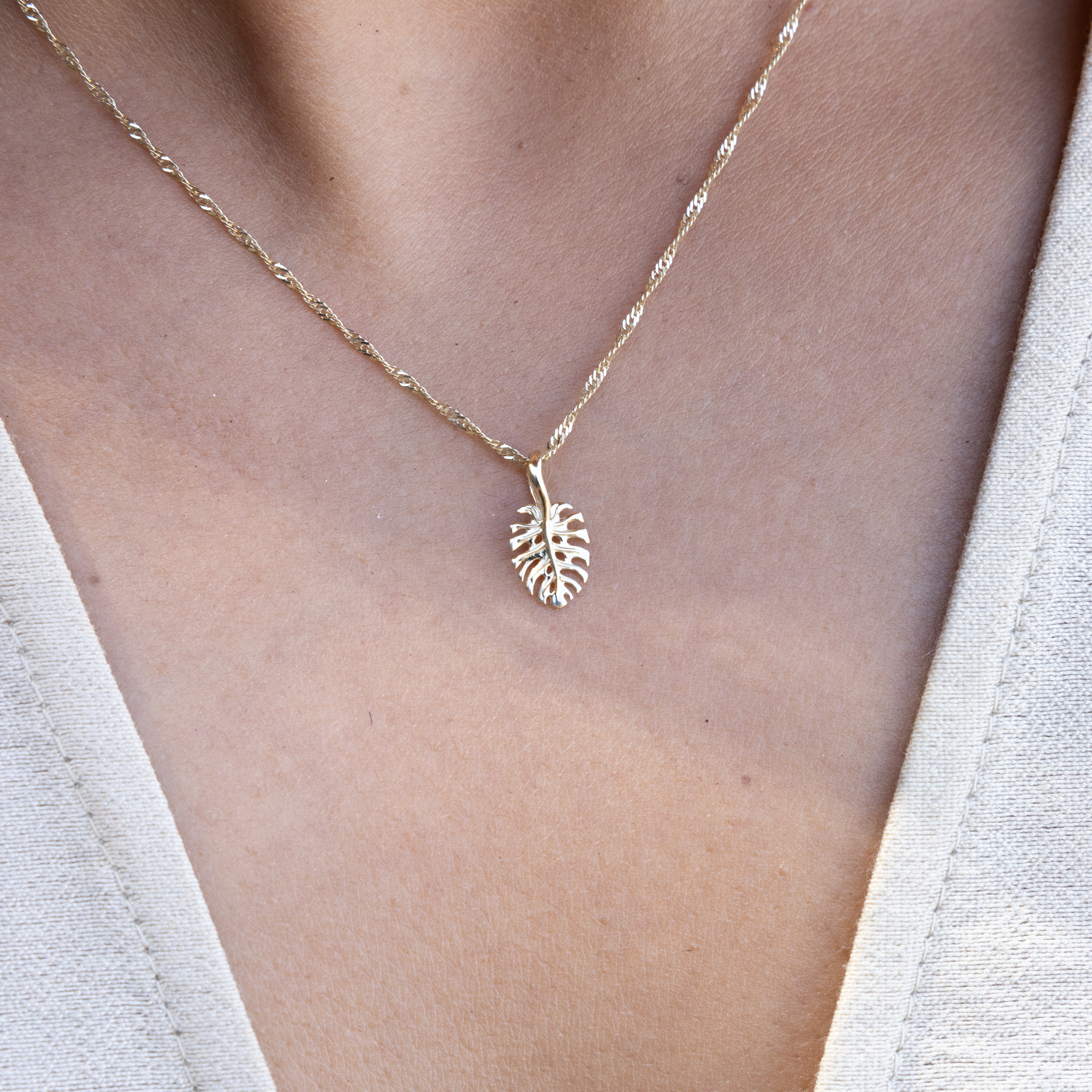 Close up of someone wearing Monstera Pendant in gold on Singapore gold chain