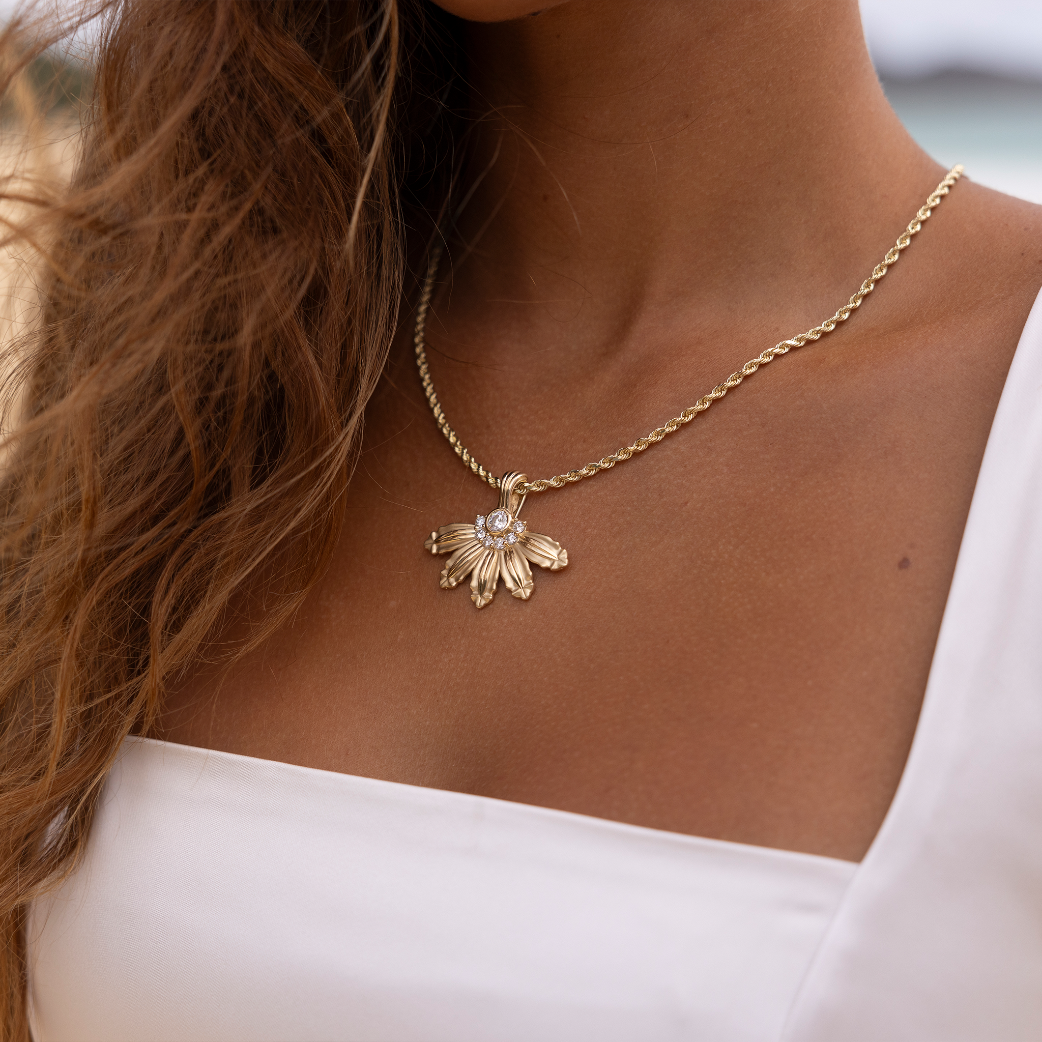 Close up of woman at the beach wearing a Mountain Naupaka Pendant in Gold with Lab Grown Diamonds