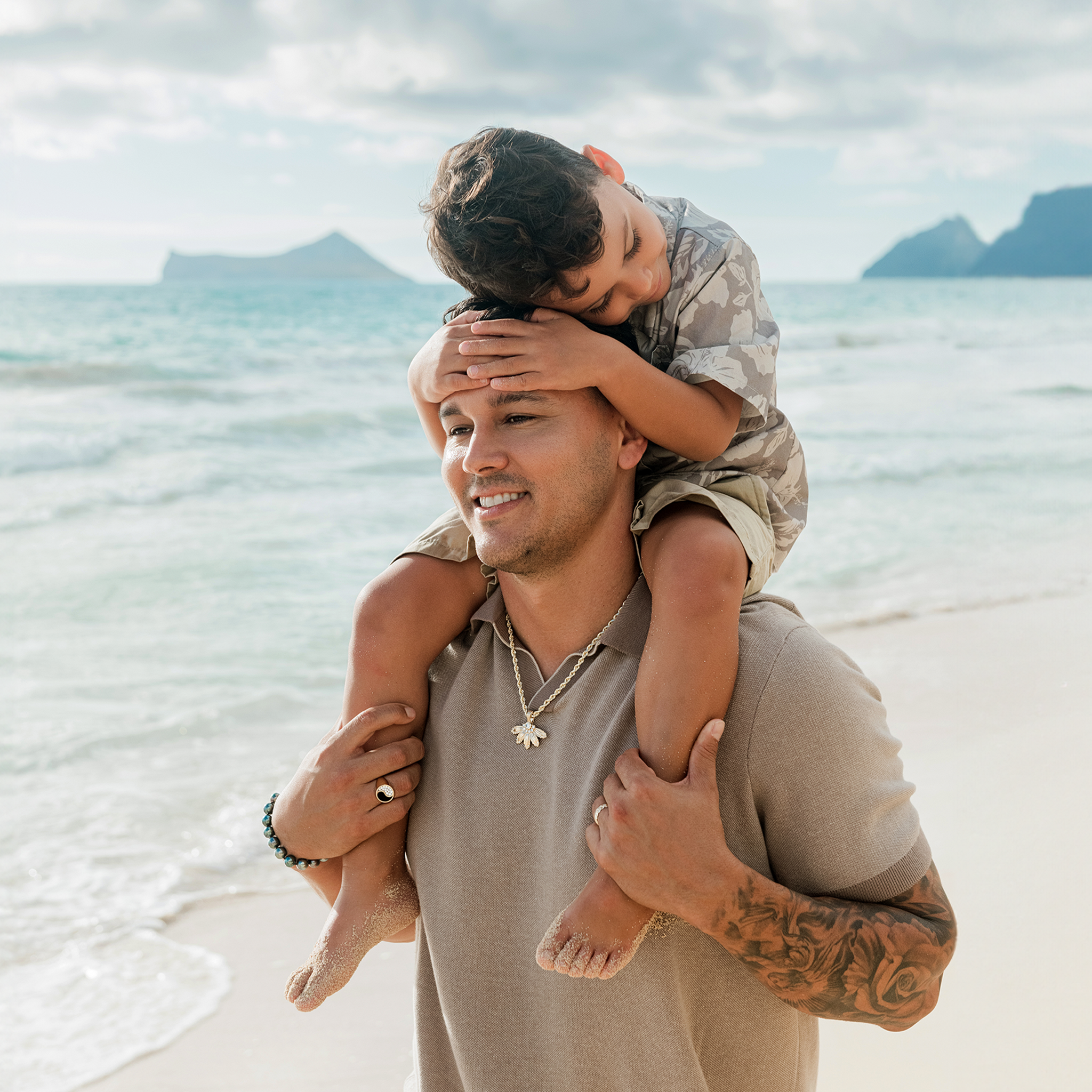 Dad and son at the beach with dad wearing the Mountain Naupaka Pendant in Gold with Lab Grown Diamonds