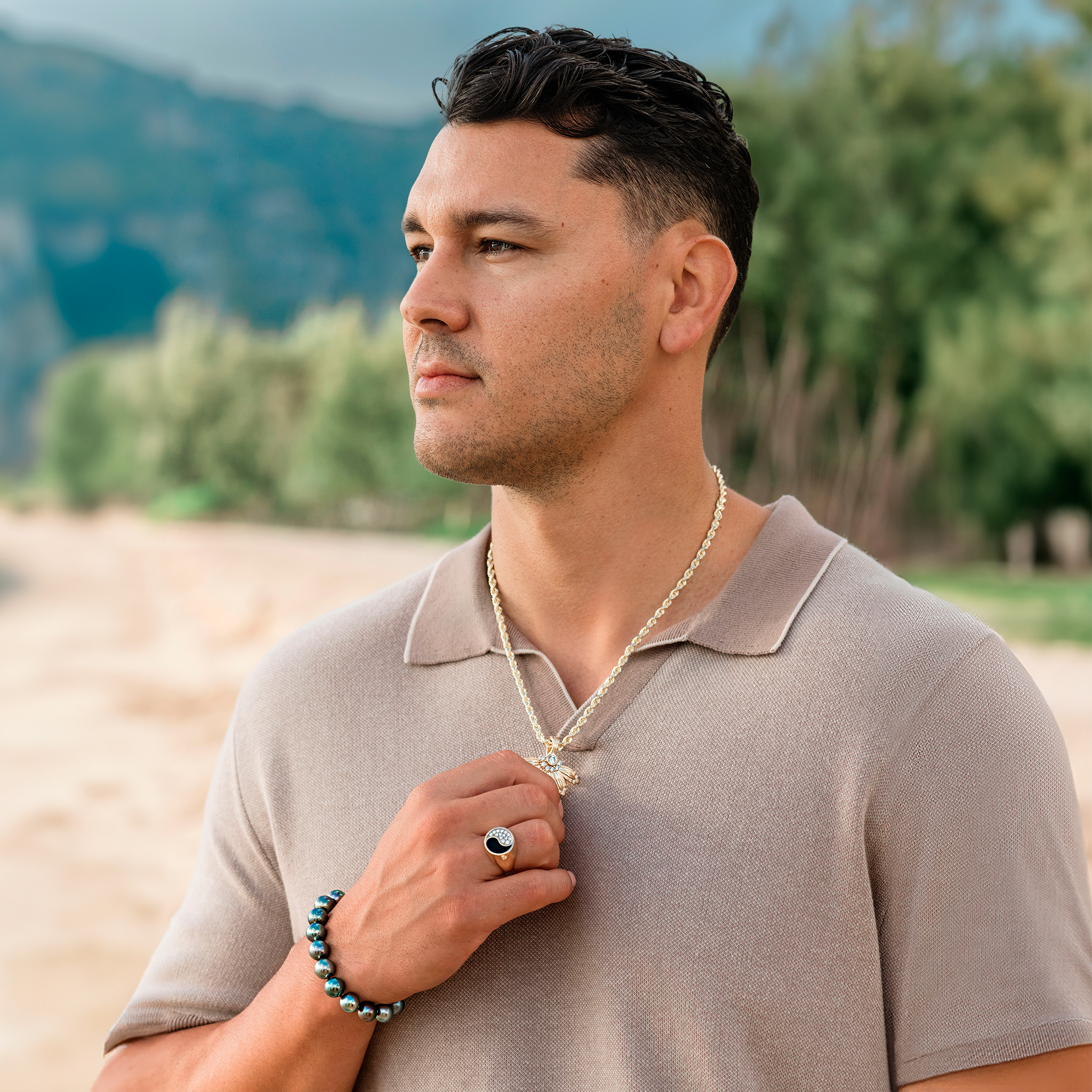 Man at the beach wearing the Mountain Naupaka Pendant in Gold with Lab Grown Diamonds