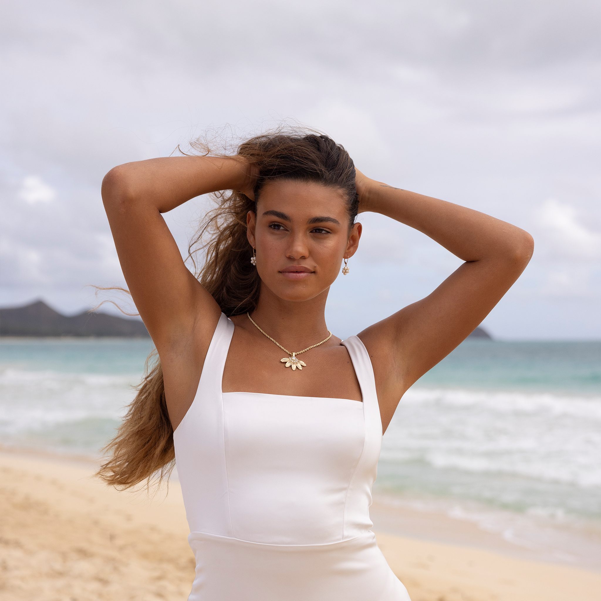 Woman at the beach wearing a Mountain Naupaka Pendant in Gold with Lab Grown Diamonds