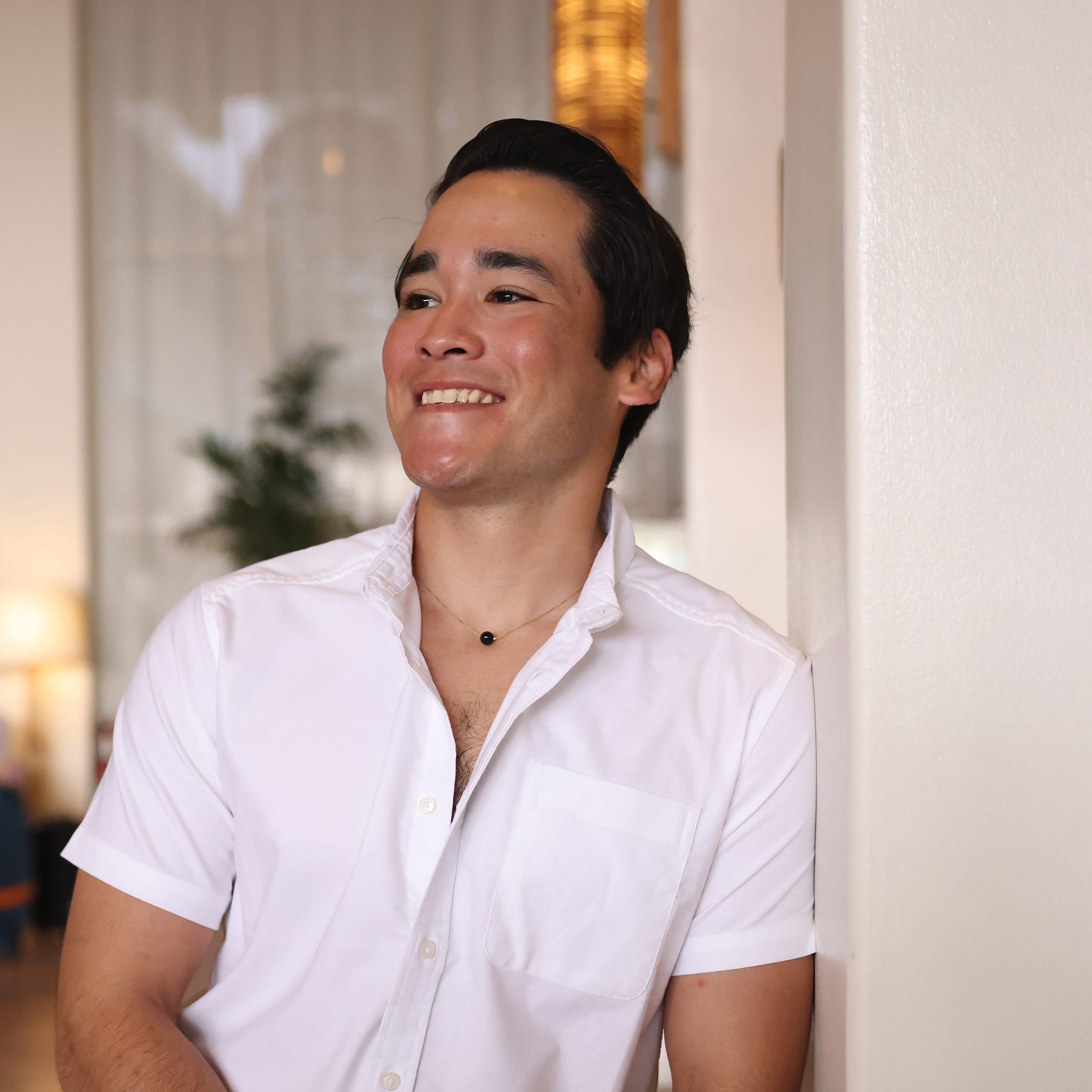 Man indoors wearing white shirt and Black Coral Slider Necklace in Gold