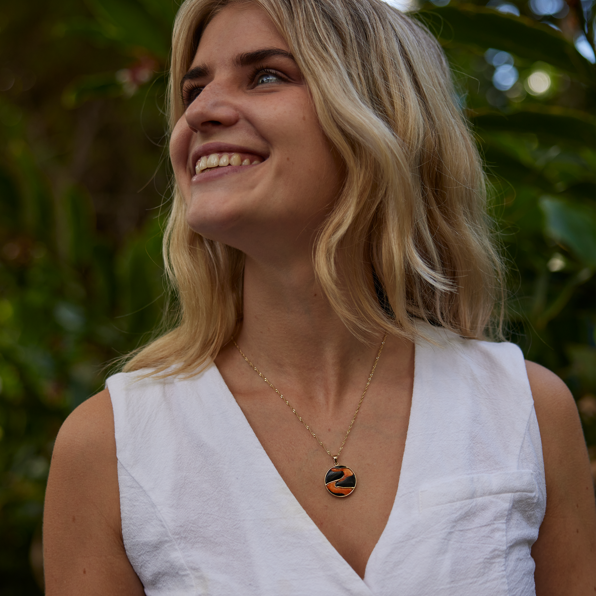 woman in garden wearing Lava Flow Black Coral and Spiny Oyster Pendant in Gold - 22mm