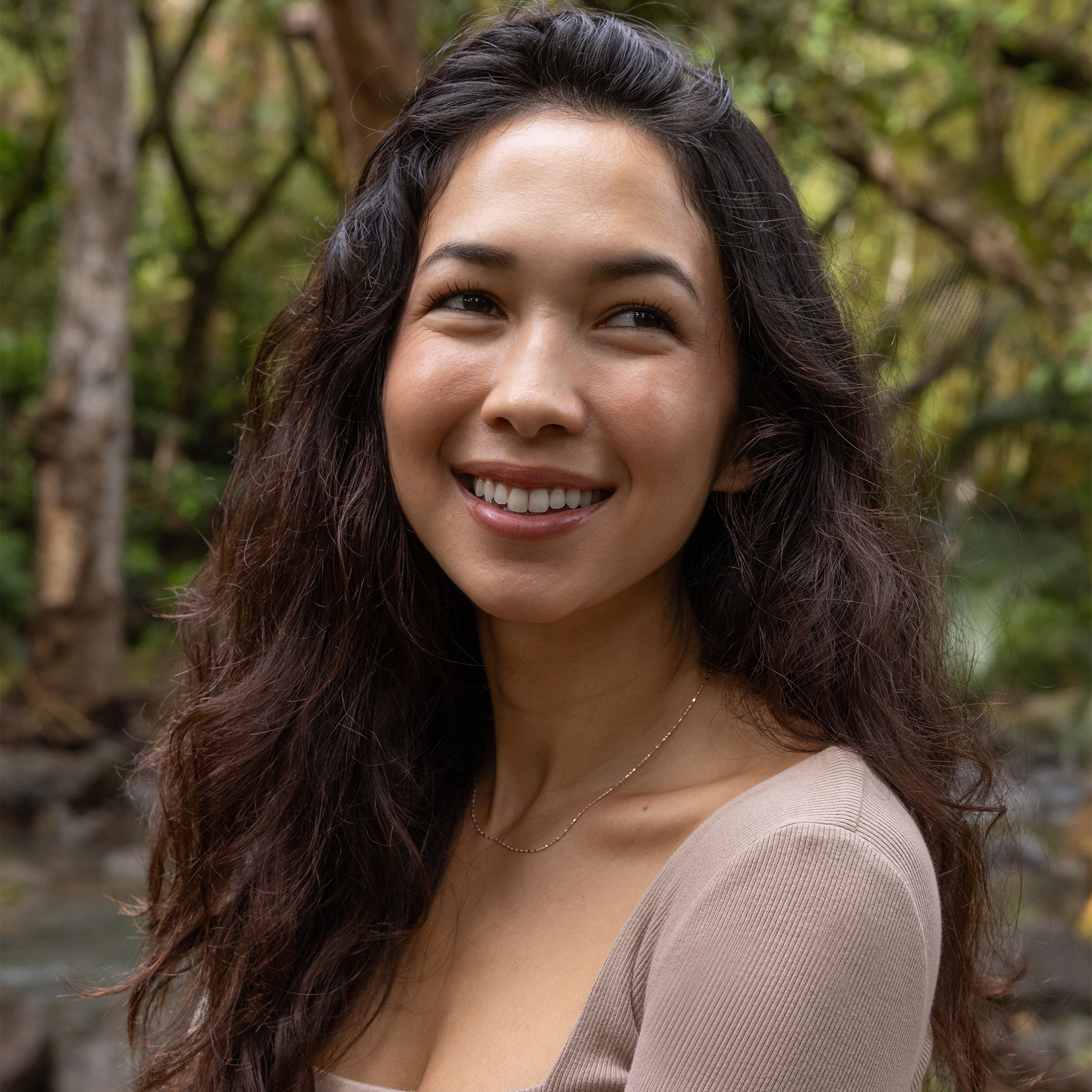 Woman smiling in a forest wearing a 1.0mm Ball Bar Chain in 14k Rose Gold