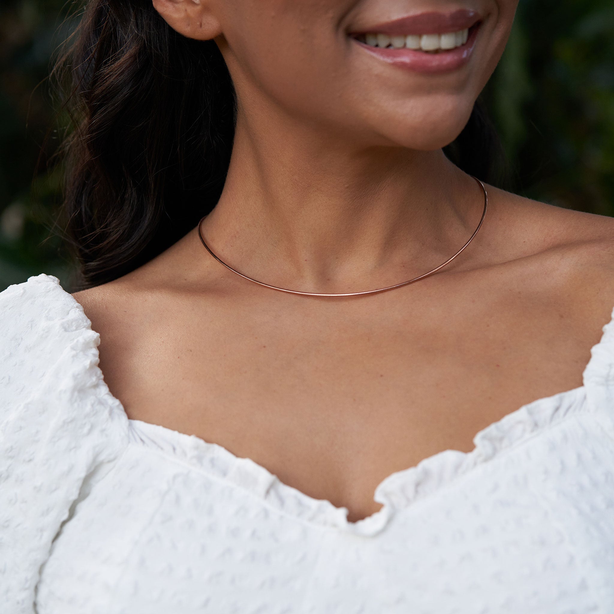 Close up of a woman wearing a white top and 1.5mm Round Omega Chain in 14k Rose Gold