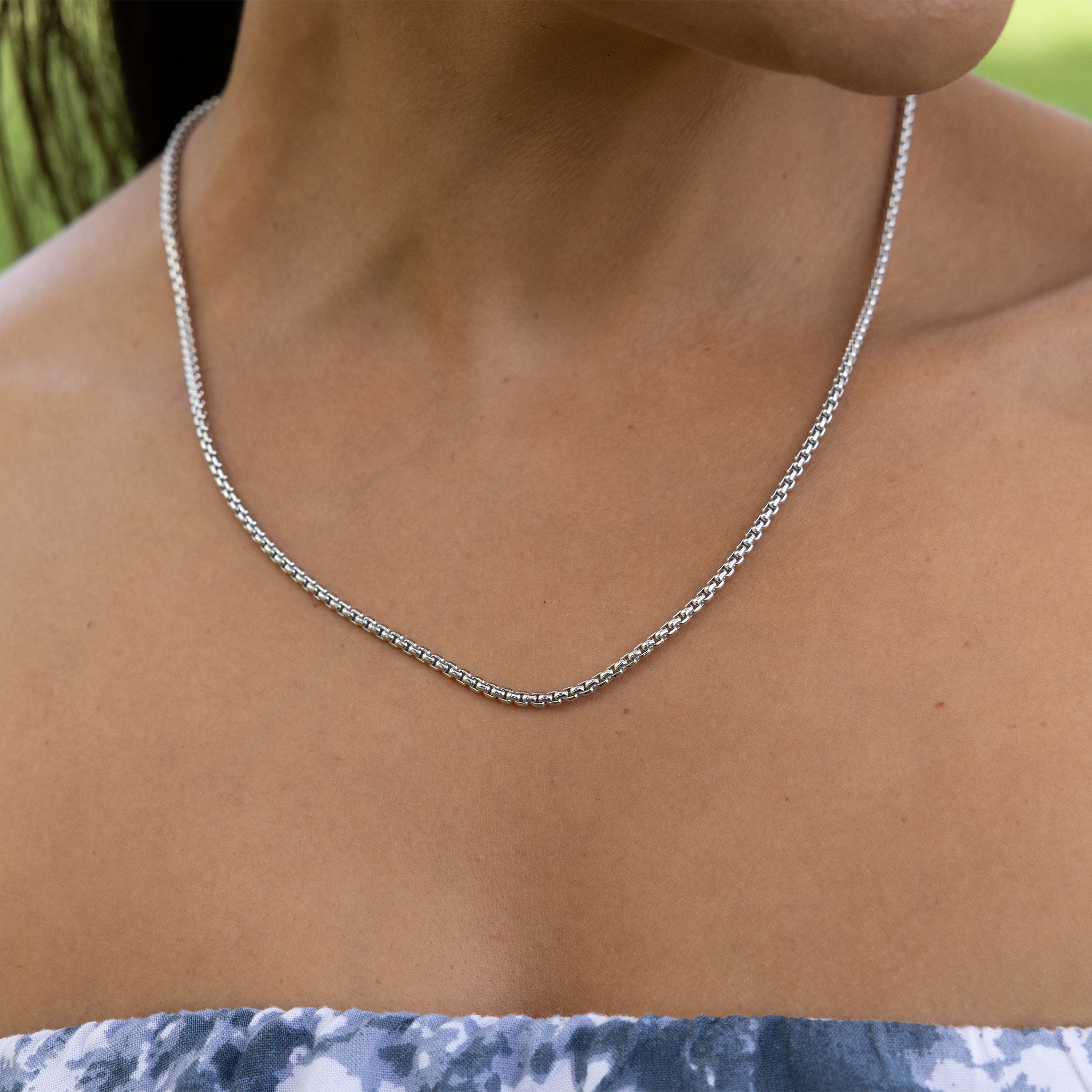 Close up of 2.5mm Round Box Chain in Sterling Silver on a neckline outdoors
