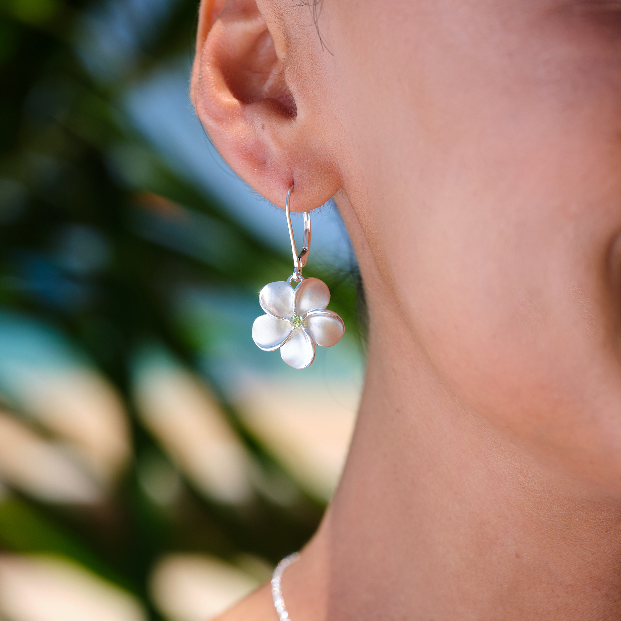 A woman's ear with a Plumeria Earrings with Peridot in Sterling Silver - 18mm-Maui Divers Jewelry