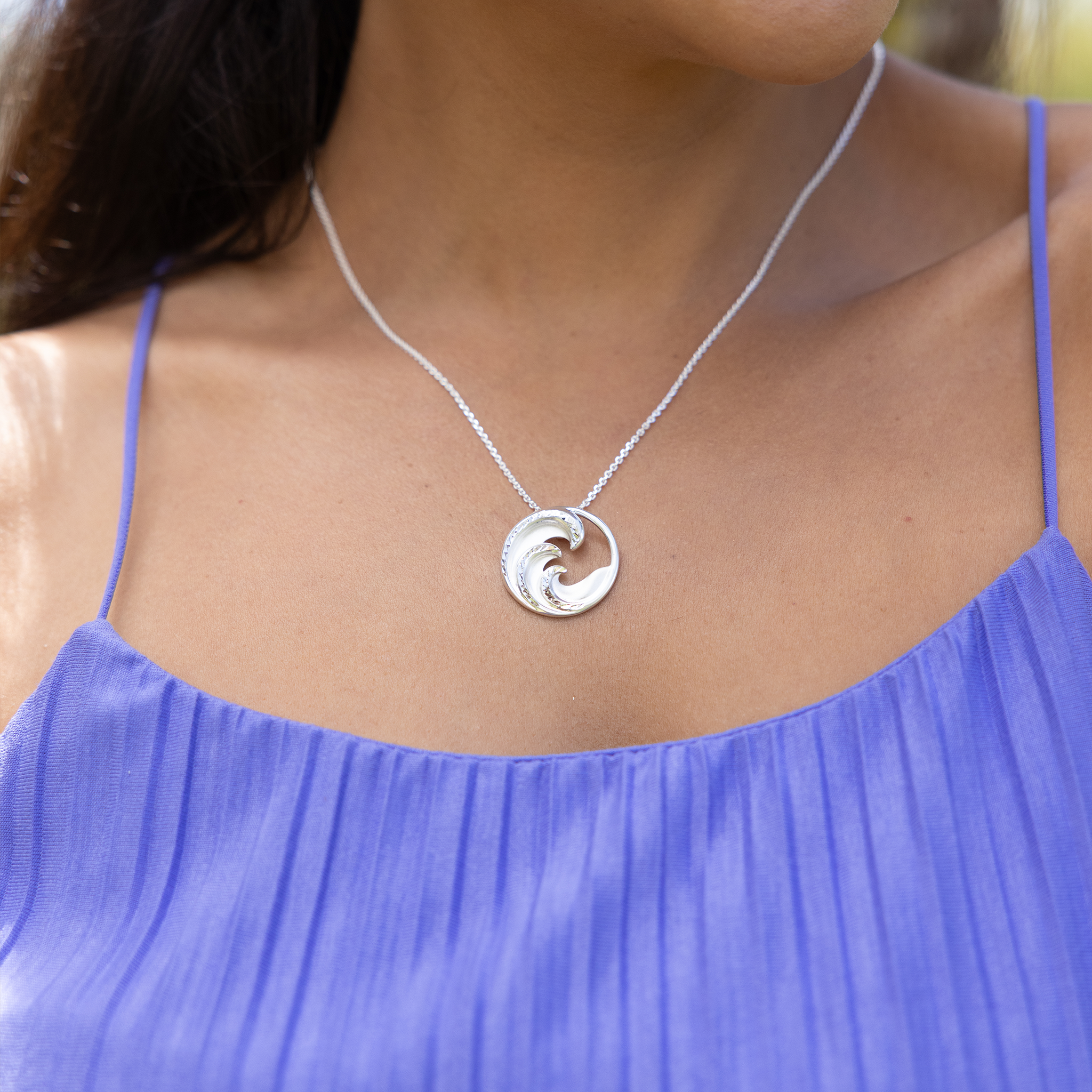 Woman wearing a purple top with a Nalu Pendant Necklace in Sterling Silver outdoors