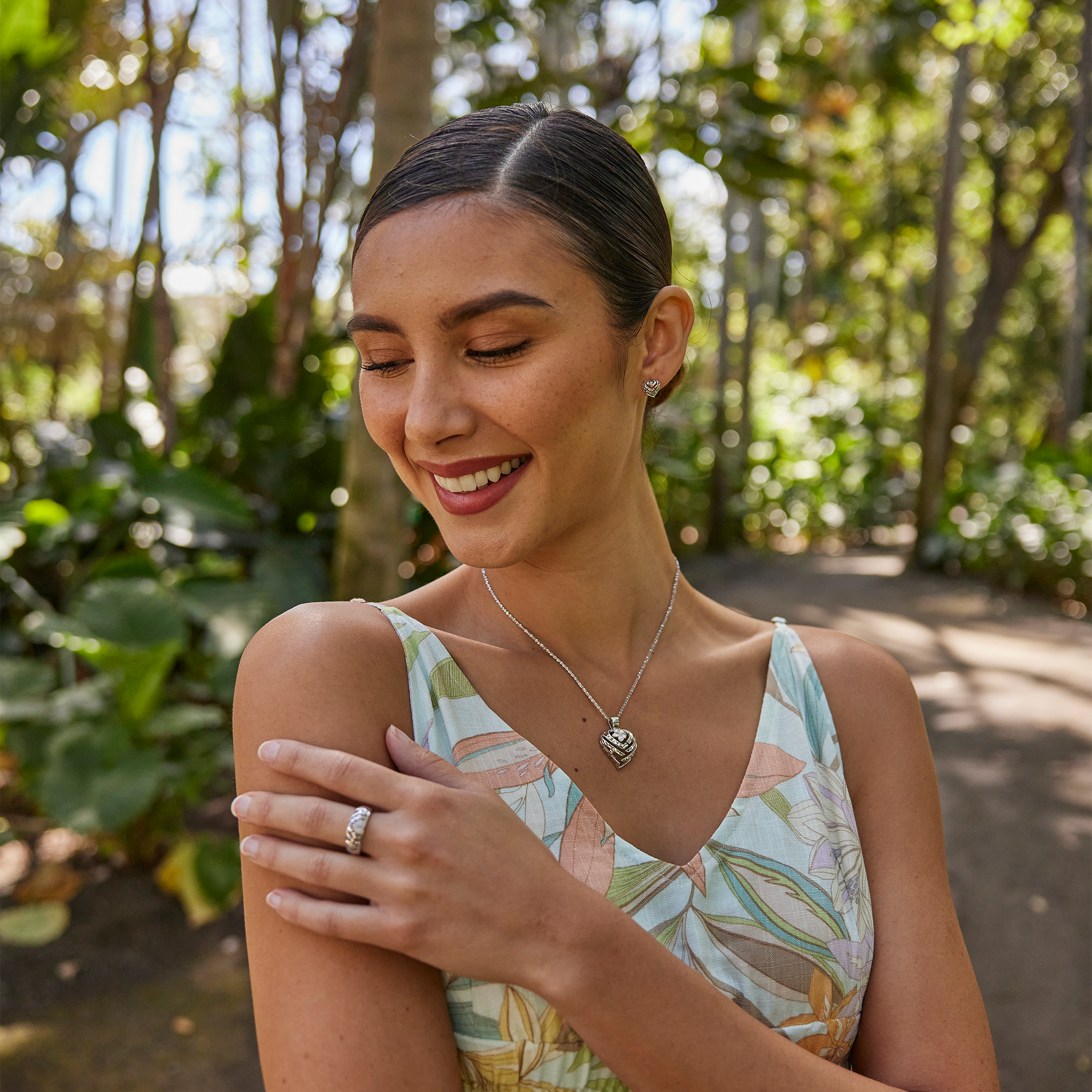 Woman in a garden wearing an Aloha Heart Plumeria Pendant in Sterling Silver