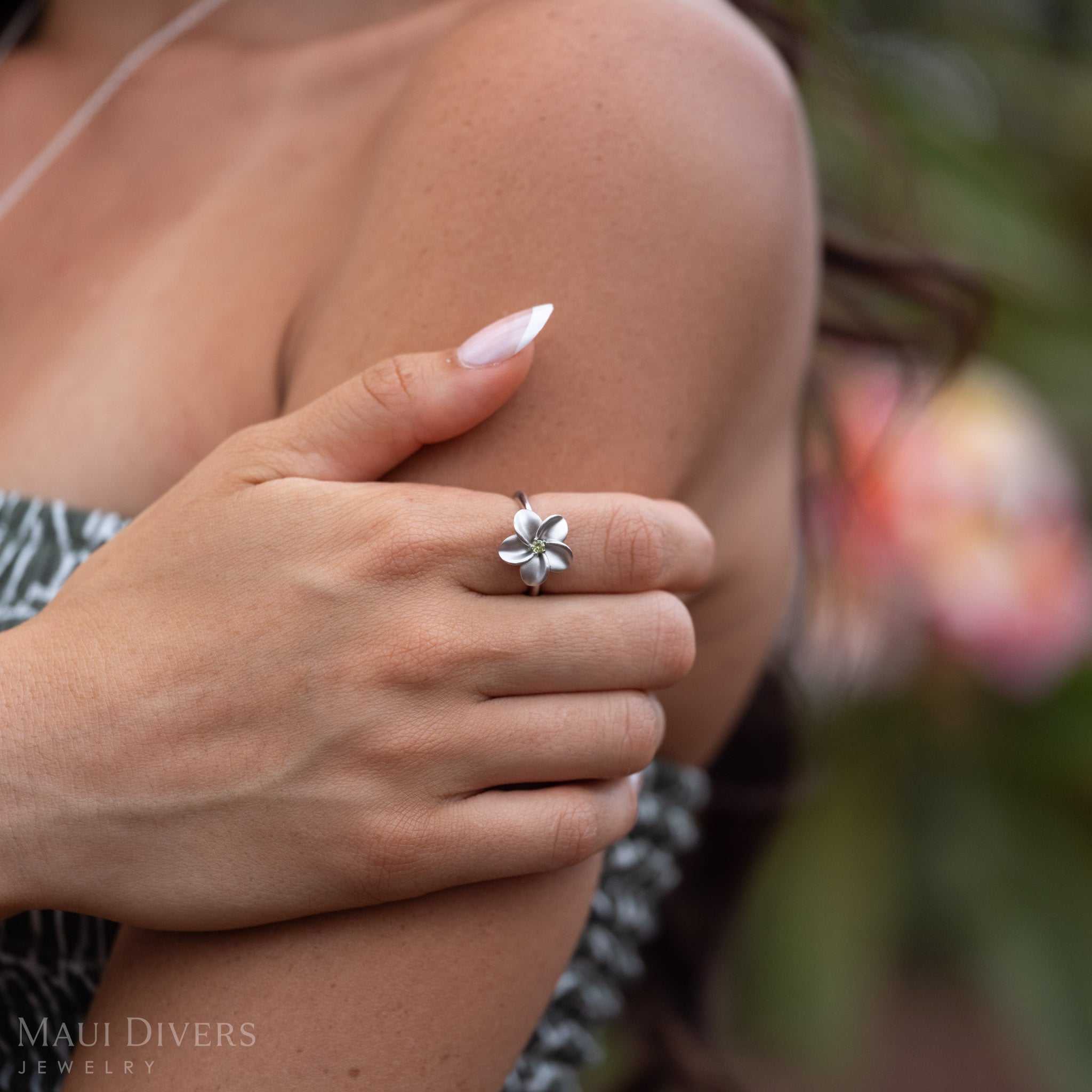 Woman with her hand wrapped around her arm wearing Plumeria Peridot Ring in Sterling Silver