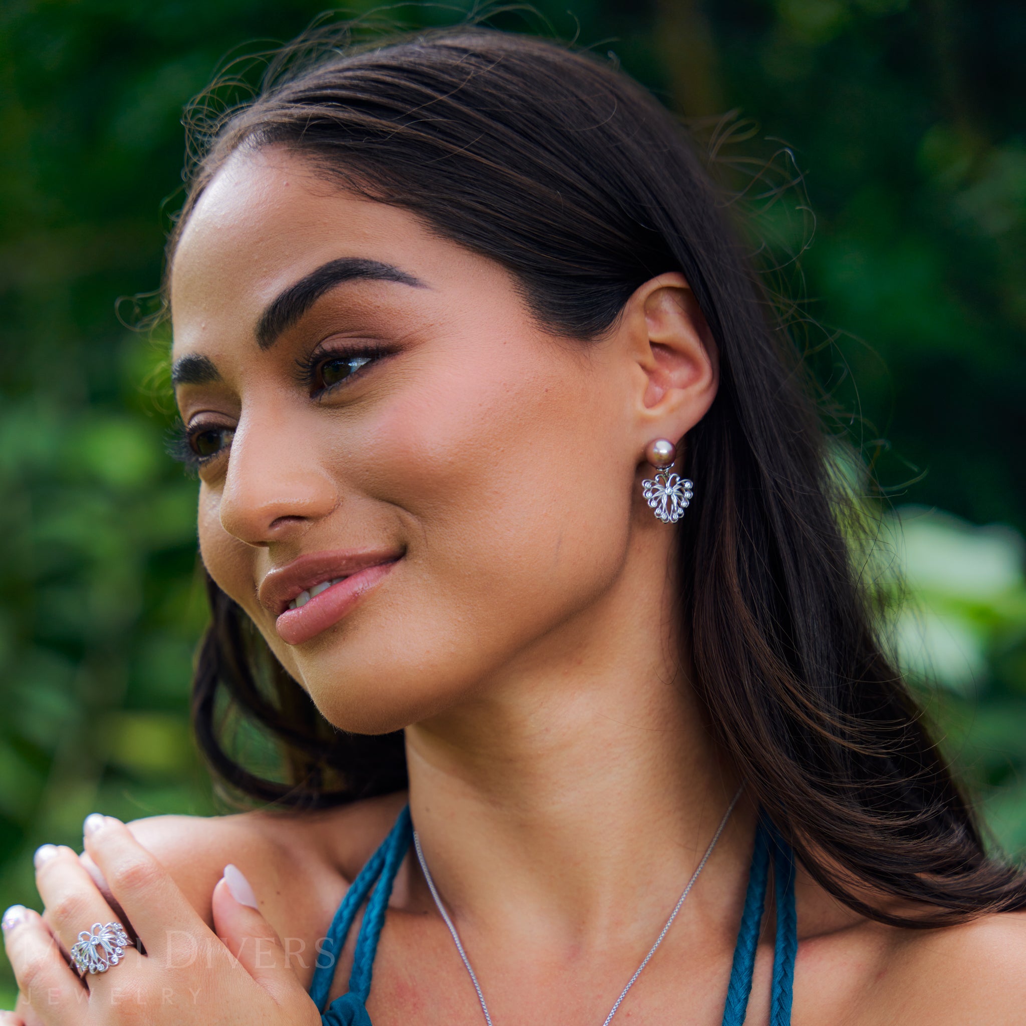 Woman wearing Butterfly Earring and ring in Sterling Silver with a blurred green background