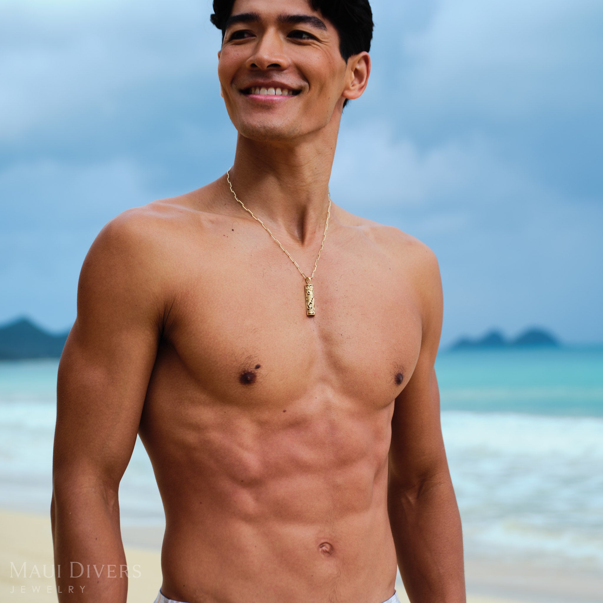 Man wearing a Hawaiian Heirloom Plumeria Pendant in Gold on a Paperclip Chain on a beach