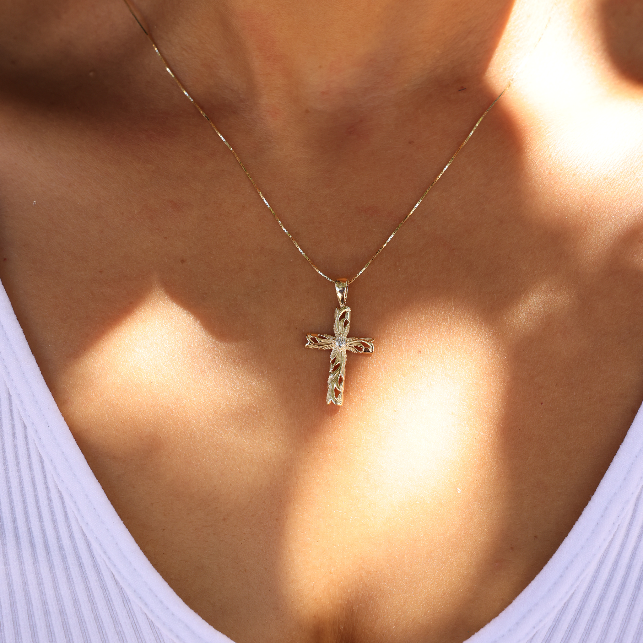 Hawaiian Heirloom Old English Scroll Cross Pendant in Gold with Diamond on Chest just below the necklace with a white shirt