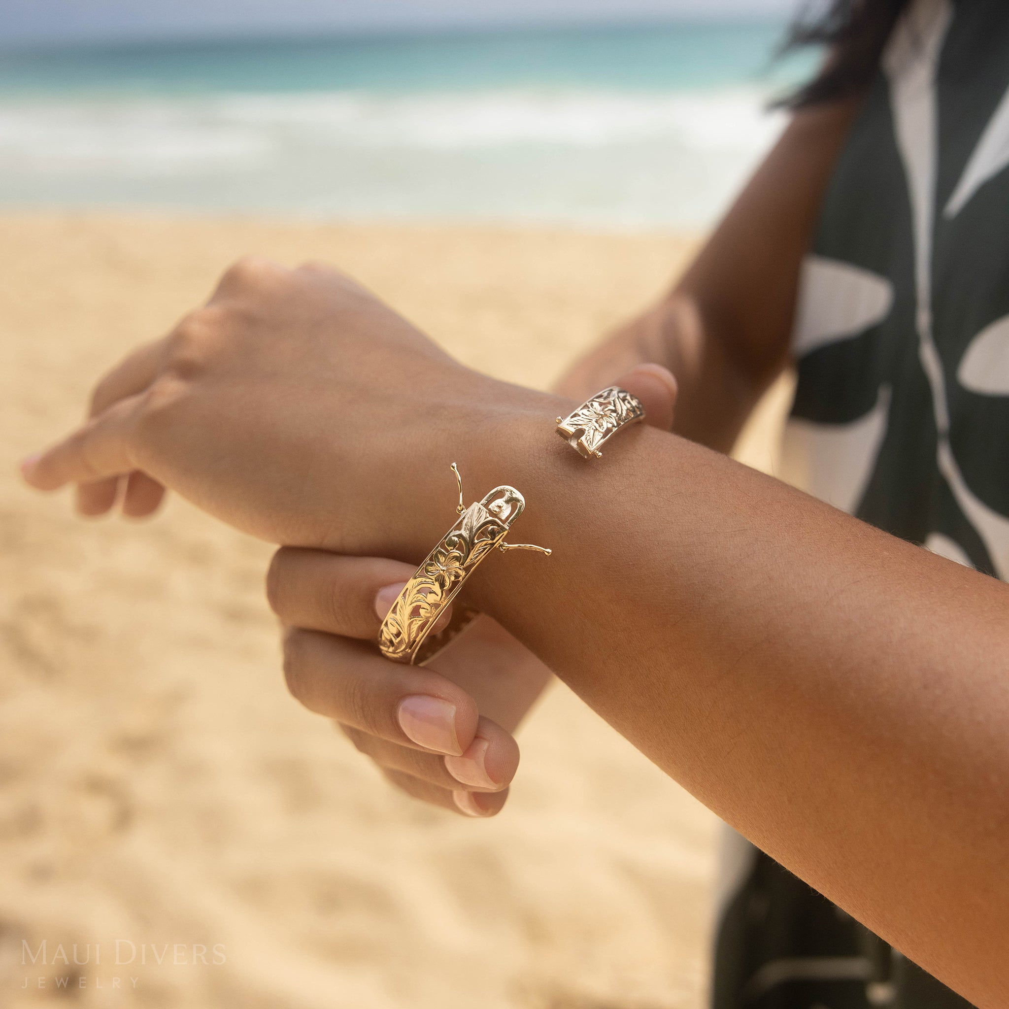 Close-up of a person's wrist showing the opening of the Hawaiian Heirloom Bracelet on a beach