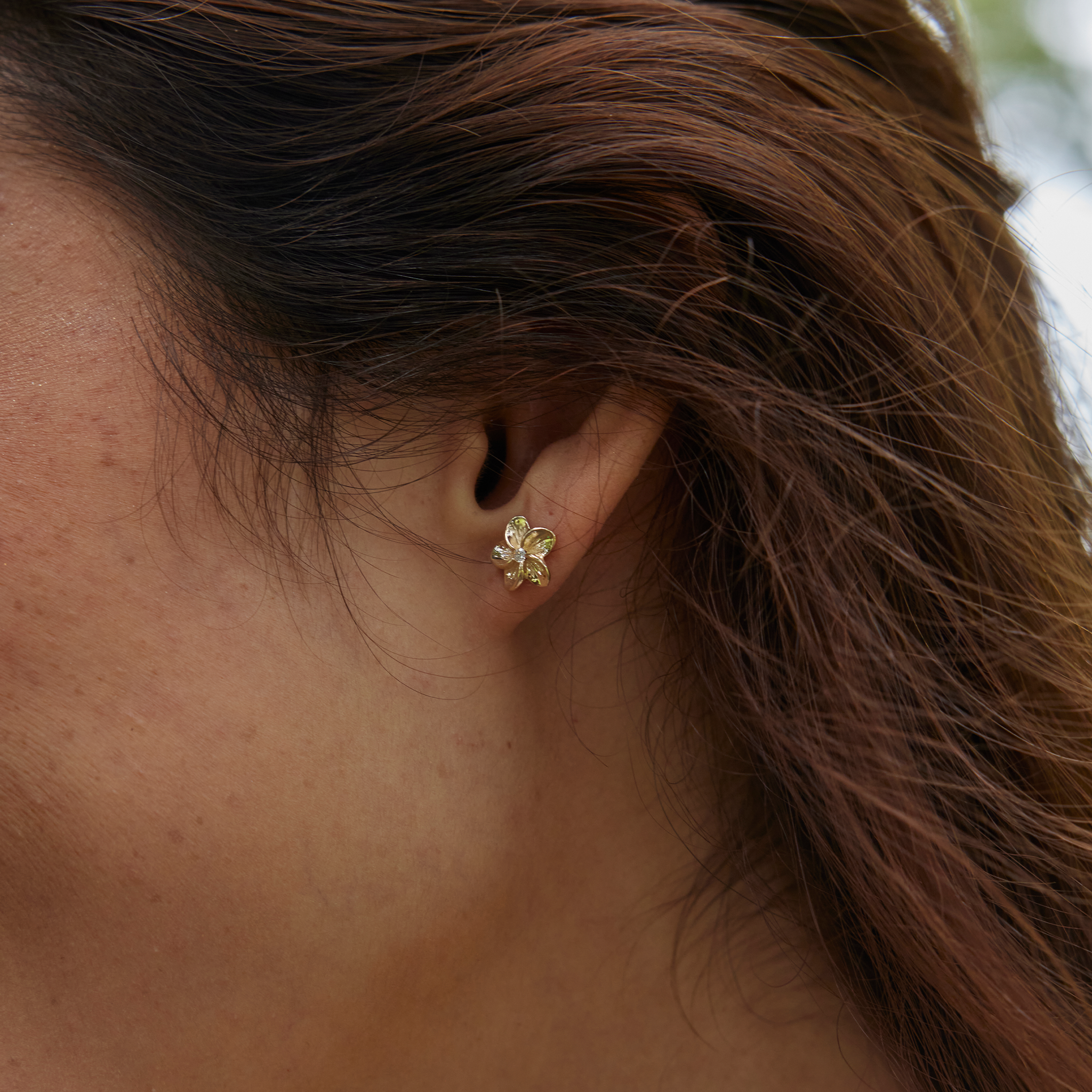 Close up of woman's ear wearing a Hawaiian Heirloom Plumeria Earring in Gold with Diamond