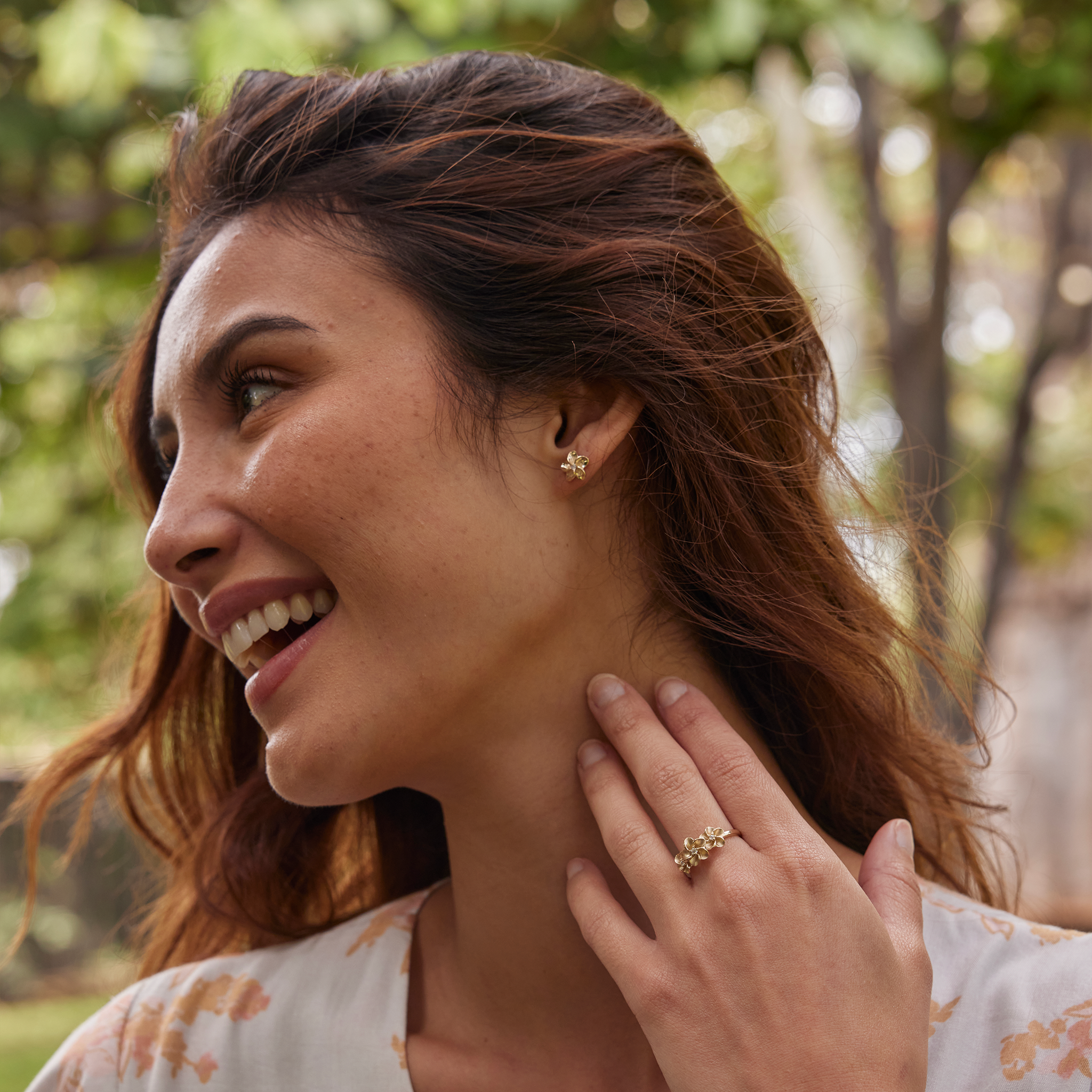 Woman in a garden wearing Hawaiian Heirloom Plumeria Earrings in Gold with Diamonds