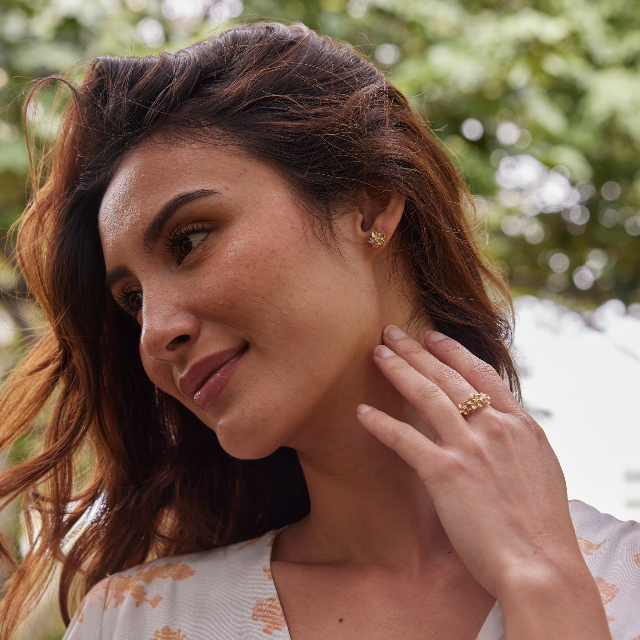 Woman in a garden wearing Hawaiian Heirloom Plumeria Earrings in Gold with Diamonds