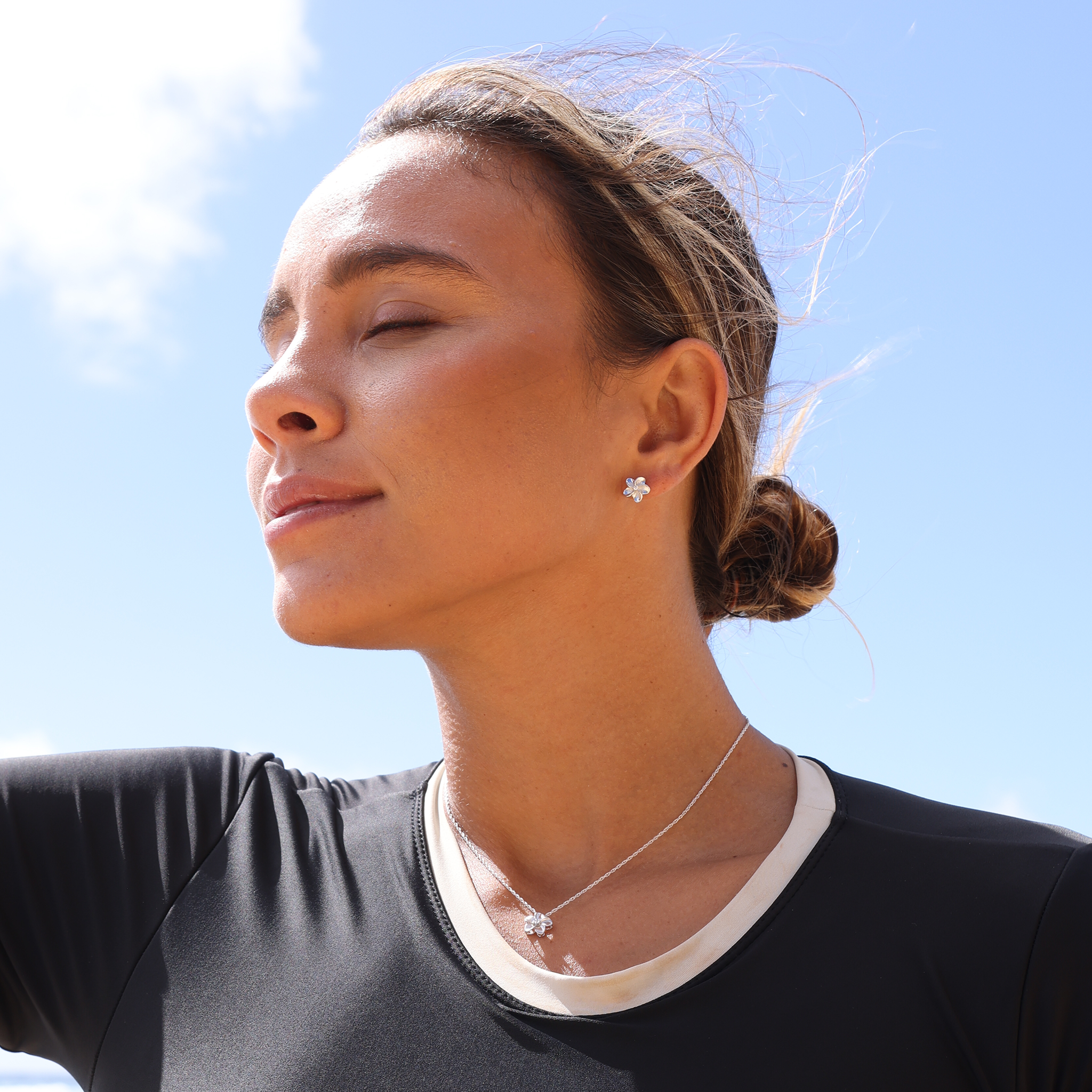 Woman outdoors with Hawaiian Heirloom Plumeria Earrings and pendant in White Gold with Diamonds