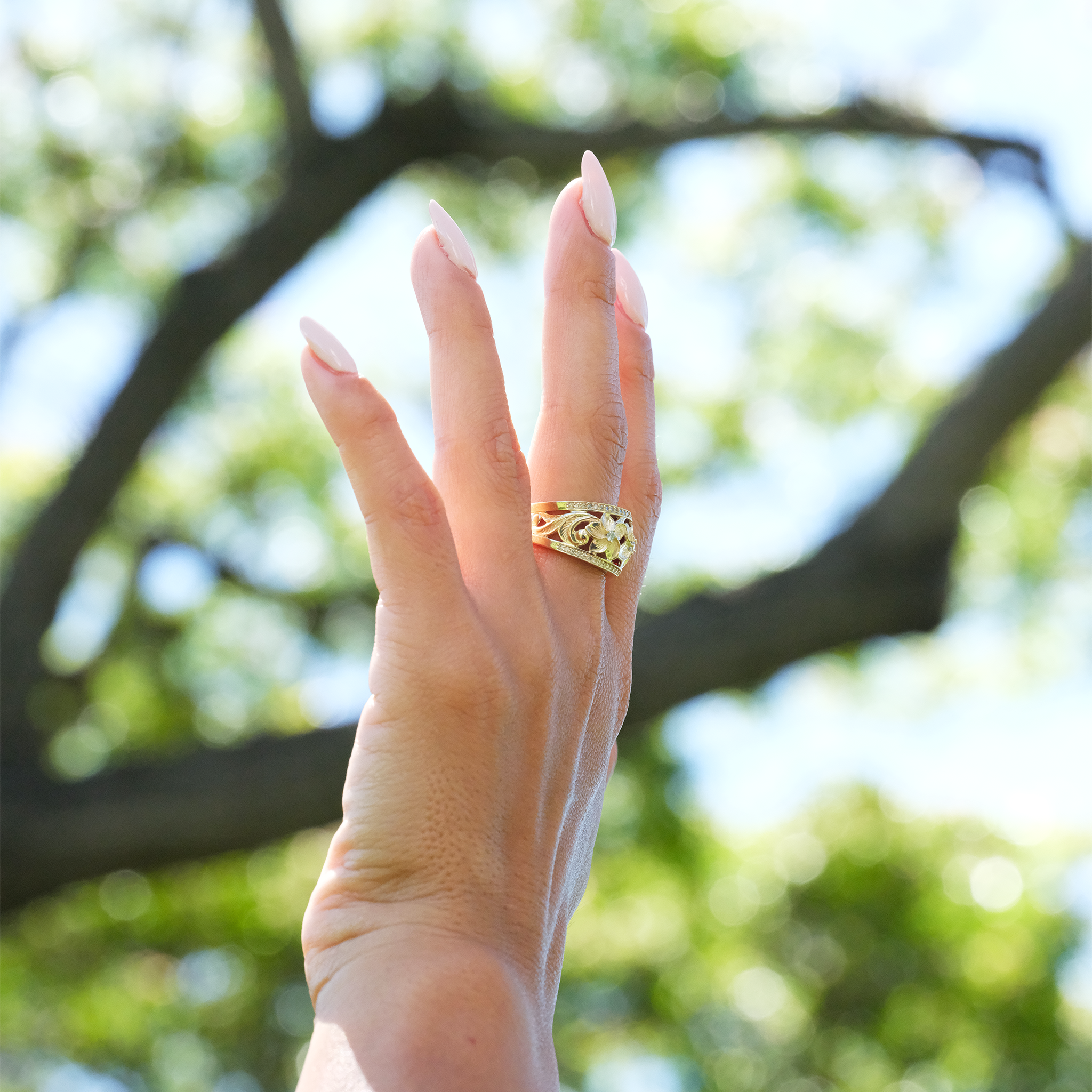 A woman's hand wearing a Hawaiian Heirloom Plumeria Ring in Gold with Diamonds - Maui divers Jewelry