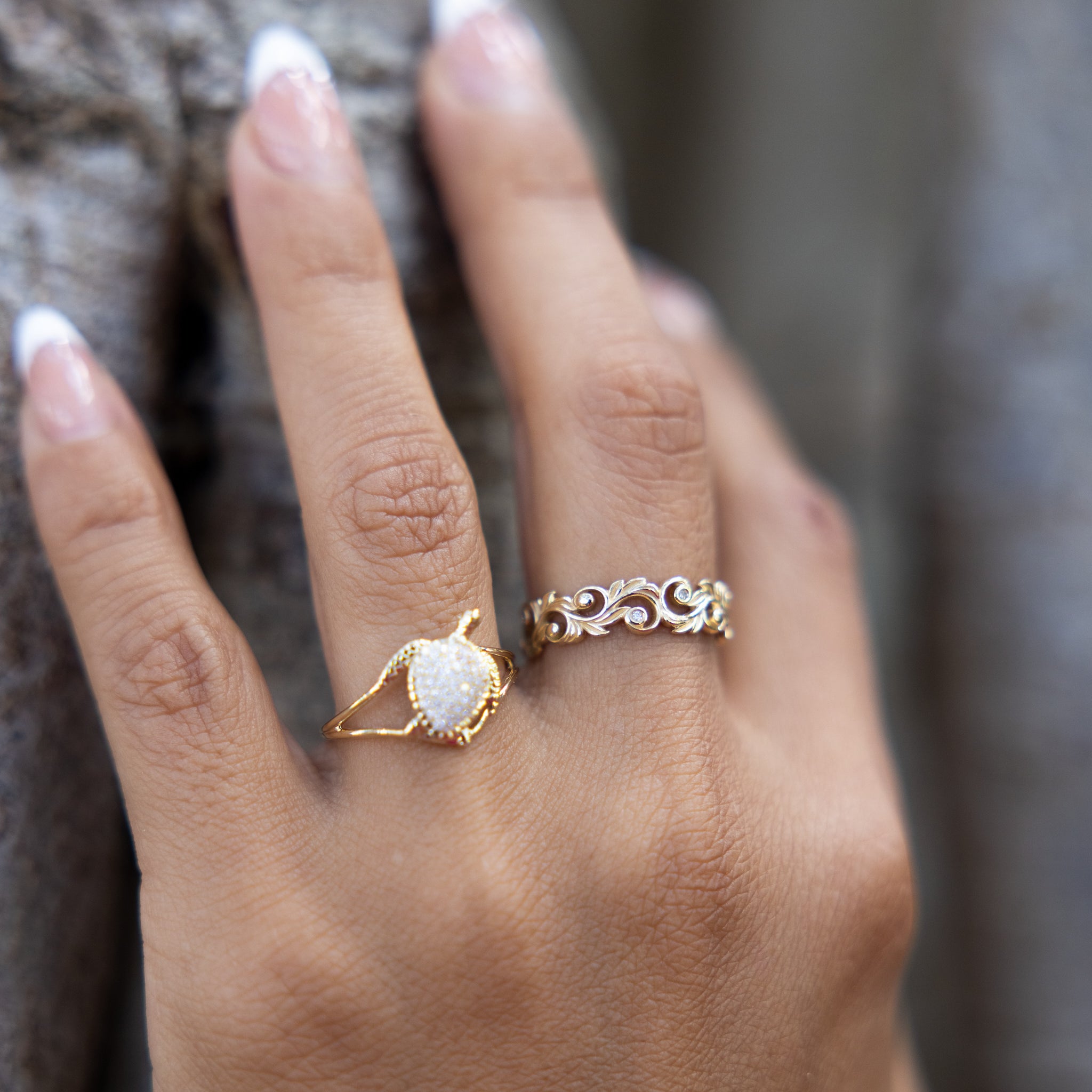 A woman's hand wearing a Living Heirloom Ring in 14k Yellow Gold with Diamonds and a honu ring