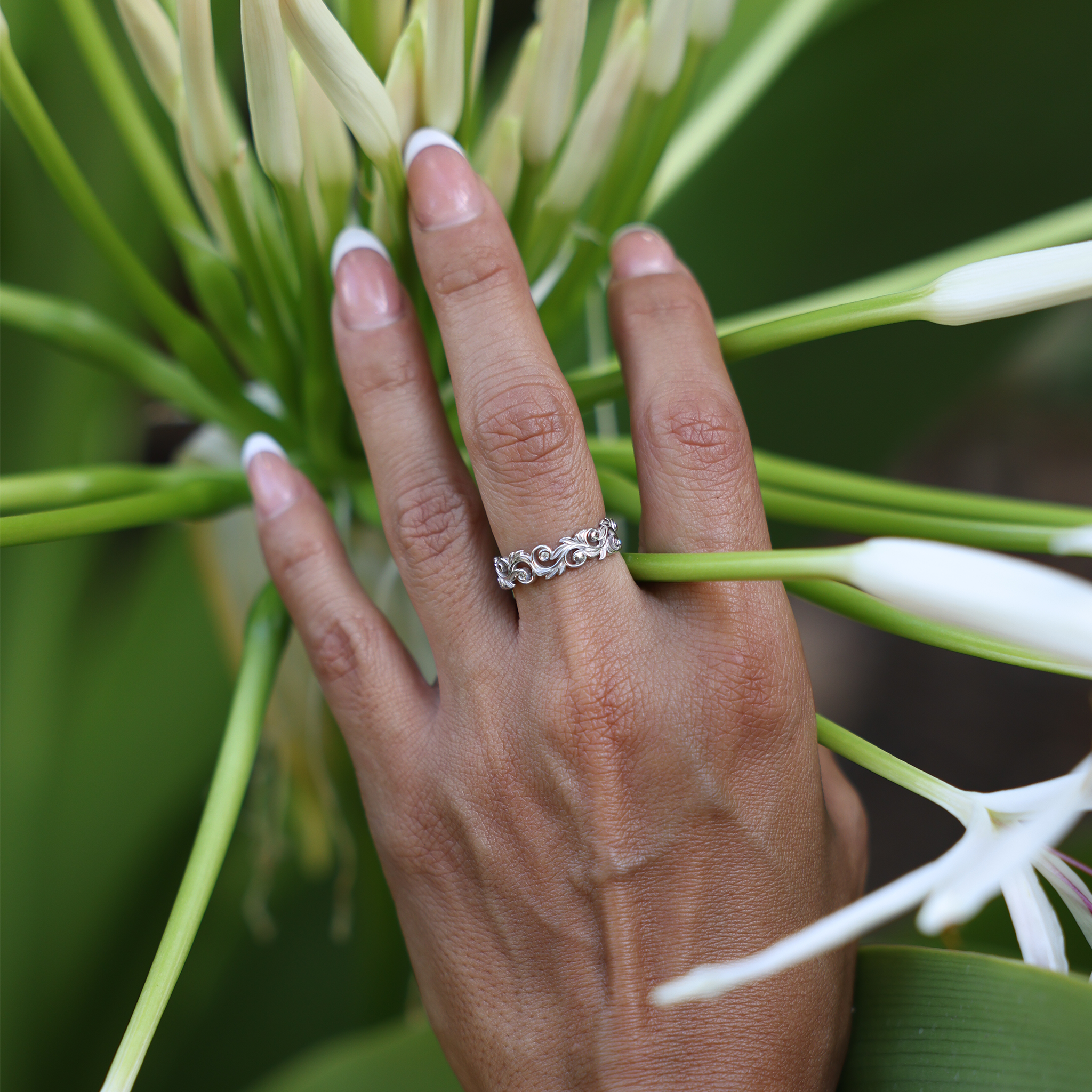 Woman's hand with Living Heirloom Ring in 14k White Gold with Diamonds against a white flower plant