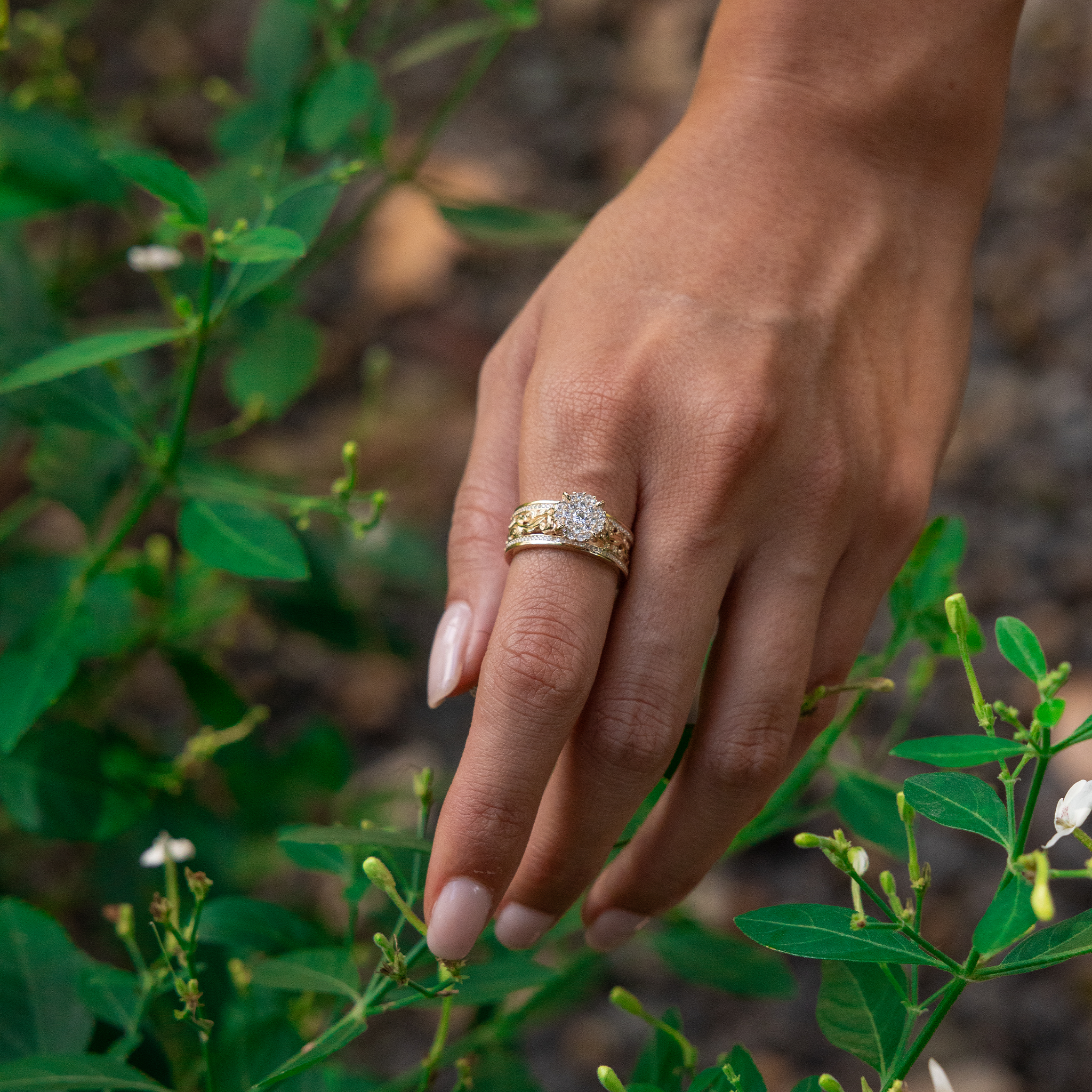 Woman's hand in a garden wearing a Living Heirloom Engagement Ring in Gold with Diamonds