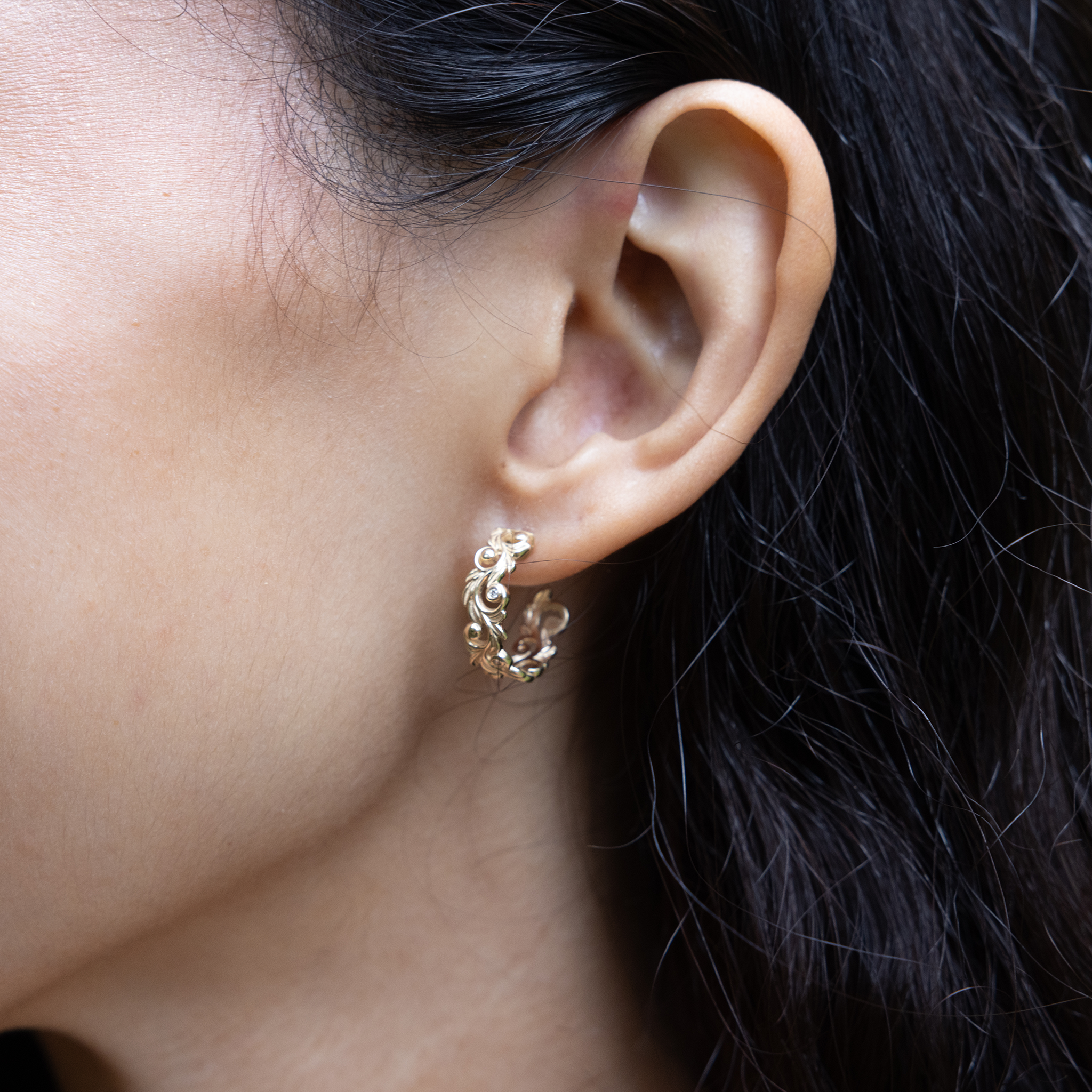 Close up of woman's left ear wearing a Living Heirloom Hoop Earring in 14k yellow gold with diamonds