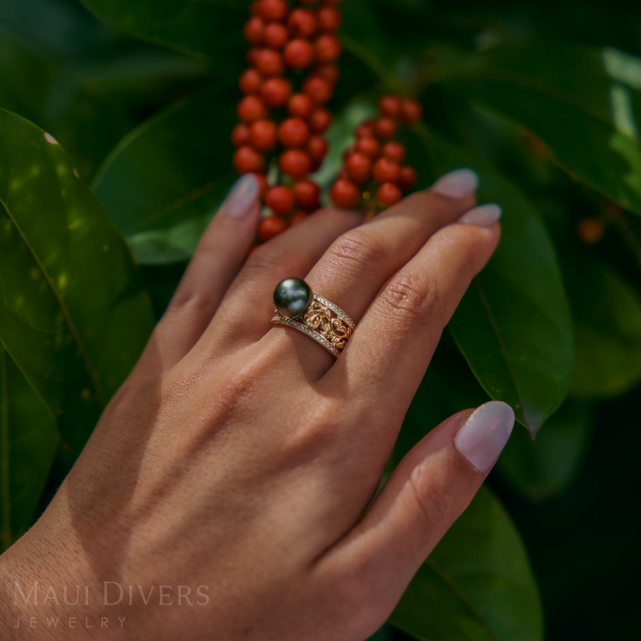Hand wearing a Living Heirloom Tahitian Black Pearl Ring in Gold with Diamonds with berries and leaves in the background