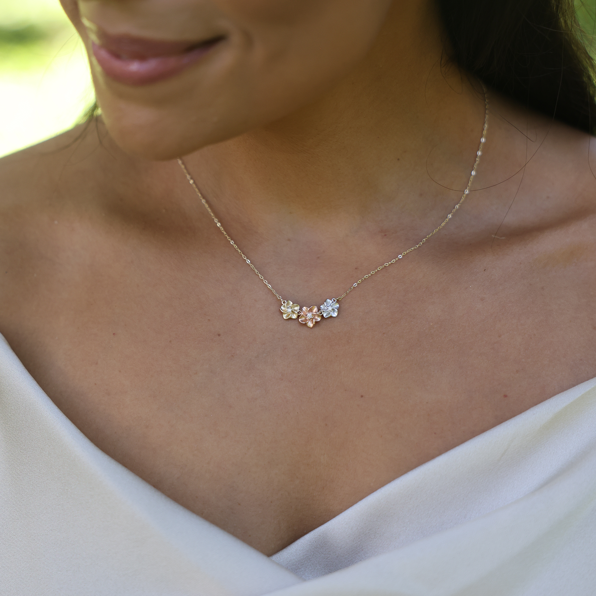16" Three Plumeria Necklace in Tri Color Gold with Diamonds on a woman's chest