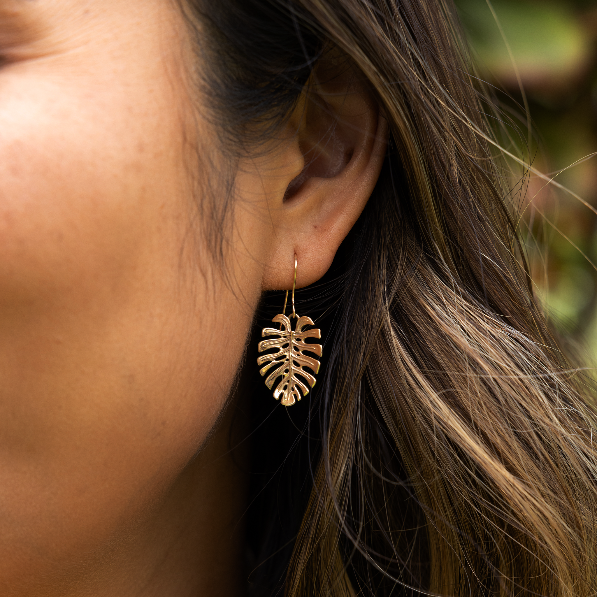Close up of 23mm Monstera Earrings in Gold on ear