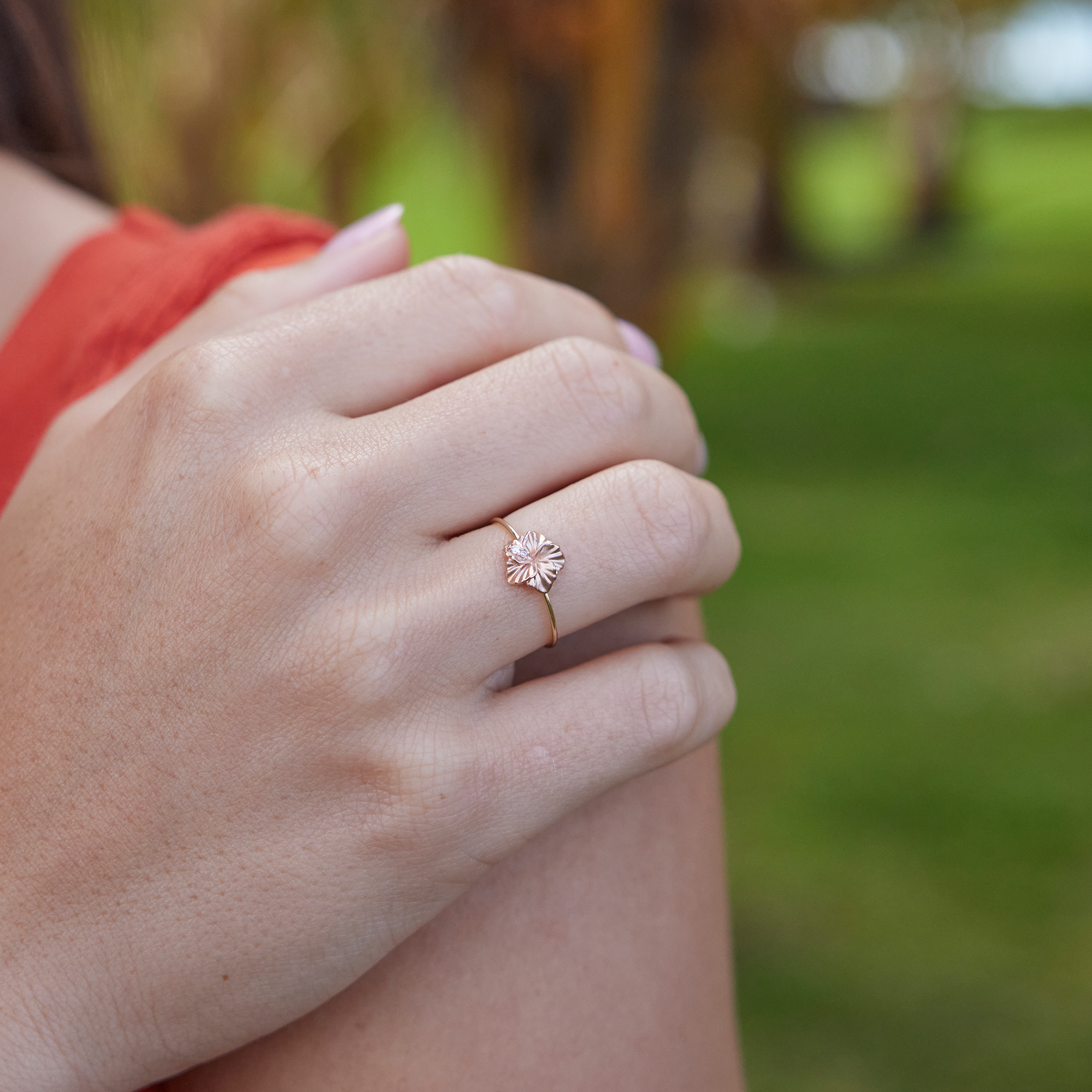 Close up of an 8mm Hawaiian Gardens Hibiscus Ring in Two Tone Gold with Diamonds on a woman's hand outdoors