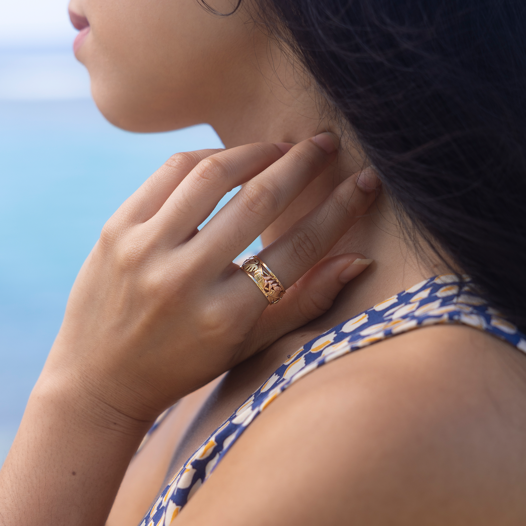 Hawaiian Gardens Monstera & Heliconia Ring in Tri Color Gold on hand with blurred ocean in the background
