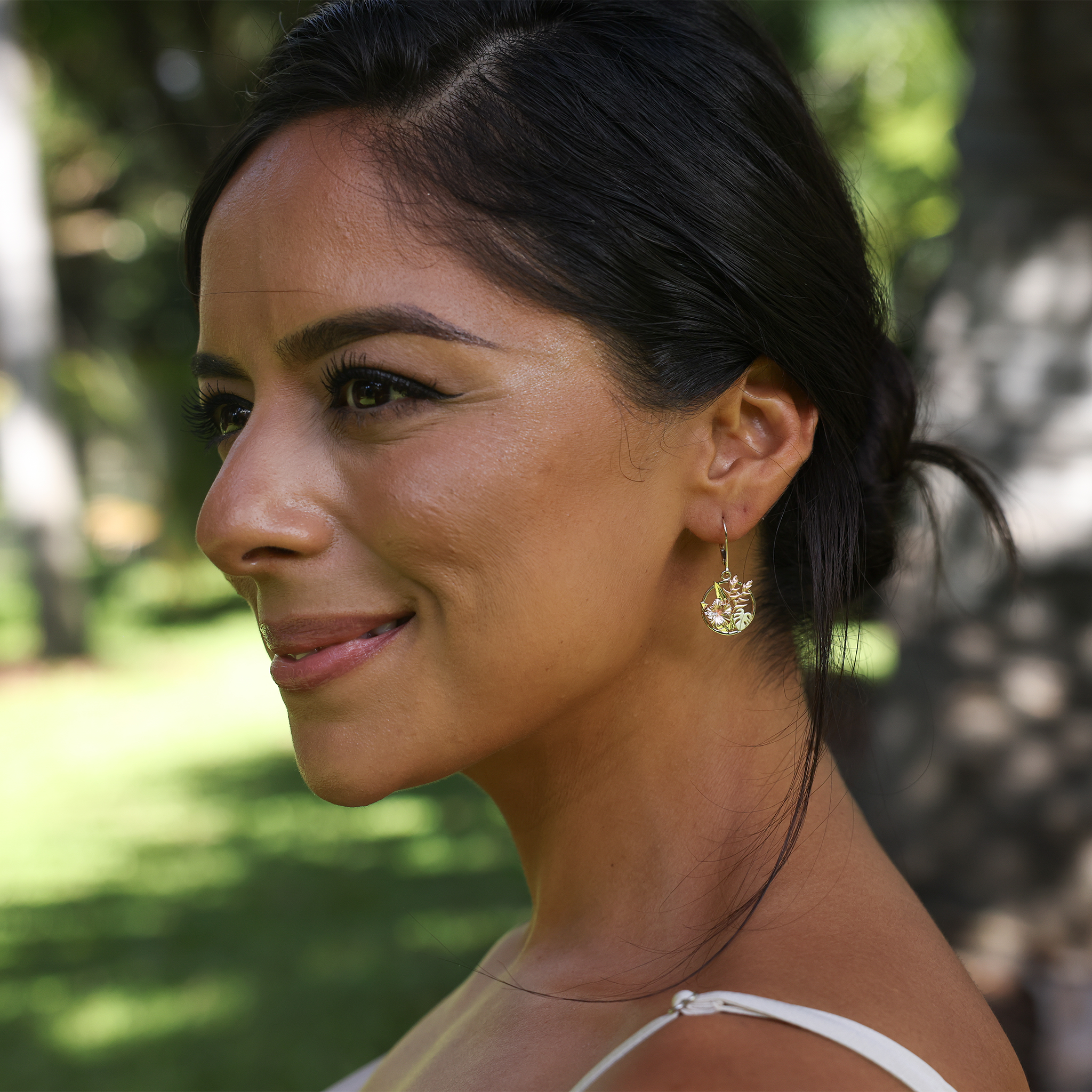 Close up of woman in a garden wearing Hawaiian Gardens Hibiscus Earrings in Tri Color Gold with Diamonds