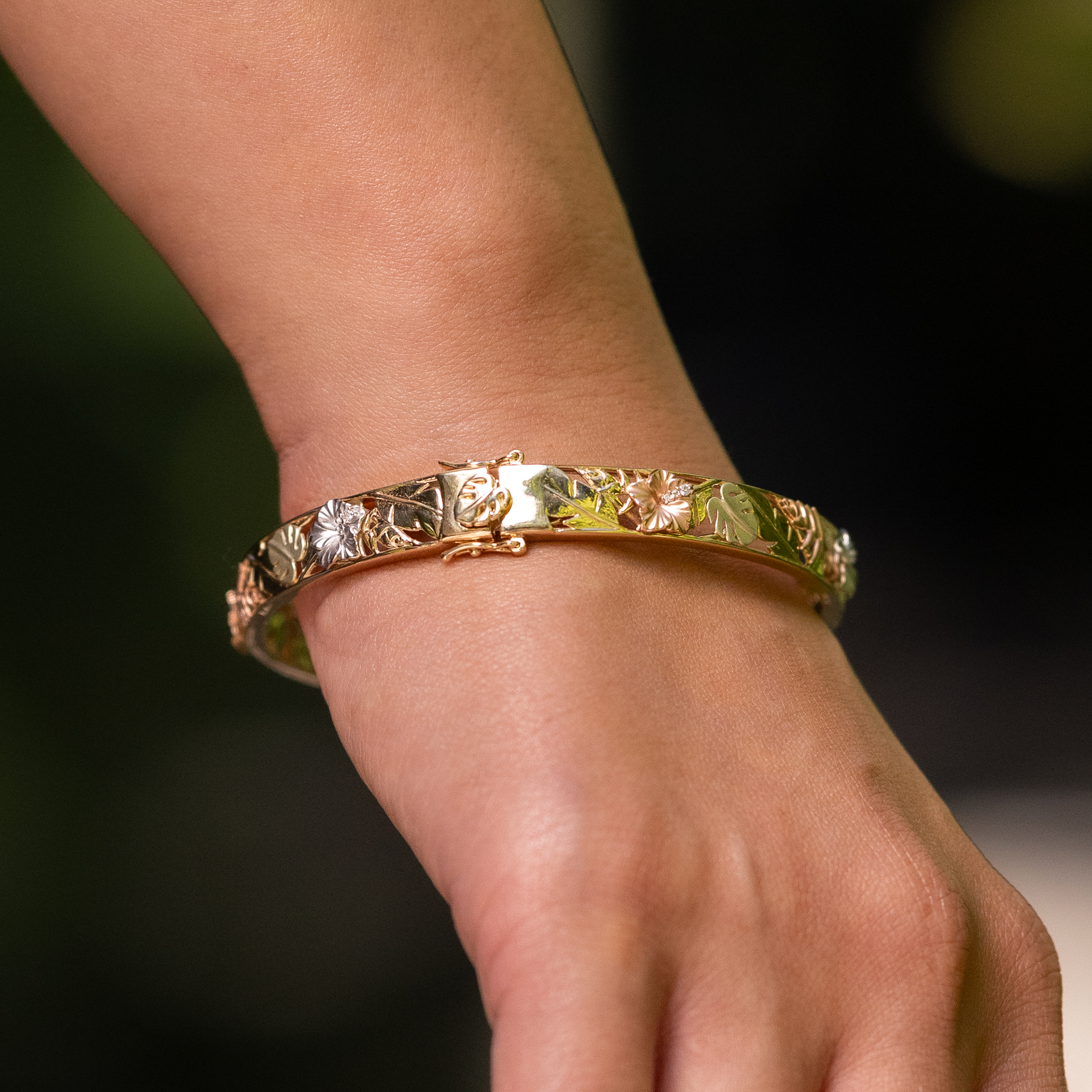Close up of hand wearing a Hawaiian Gardens Hinge Bracelet in Four Color Gold with Diamonds