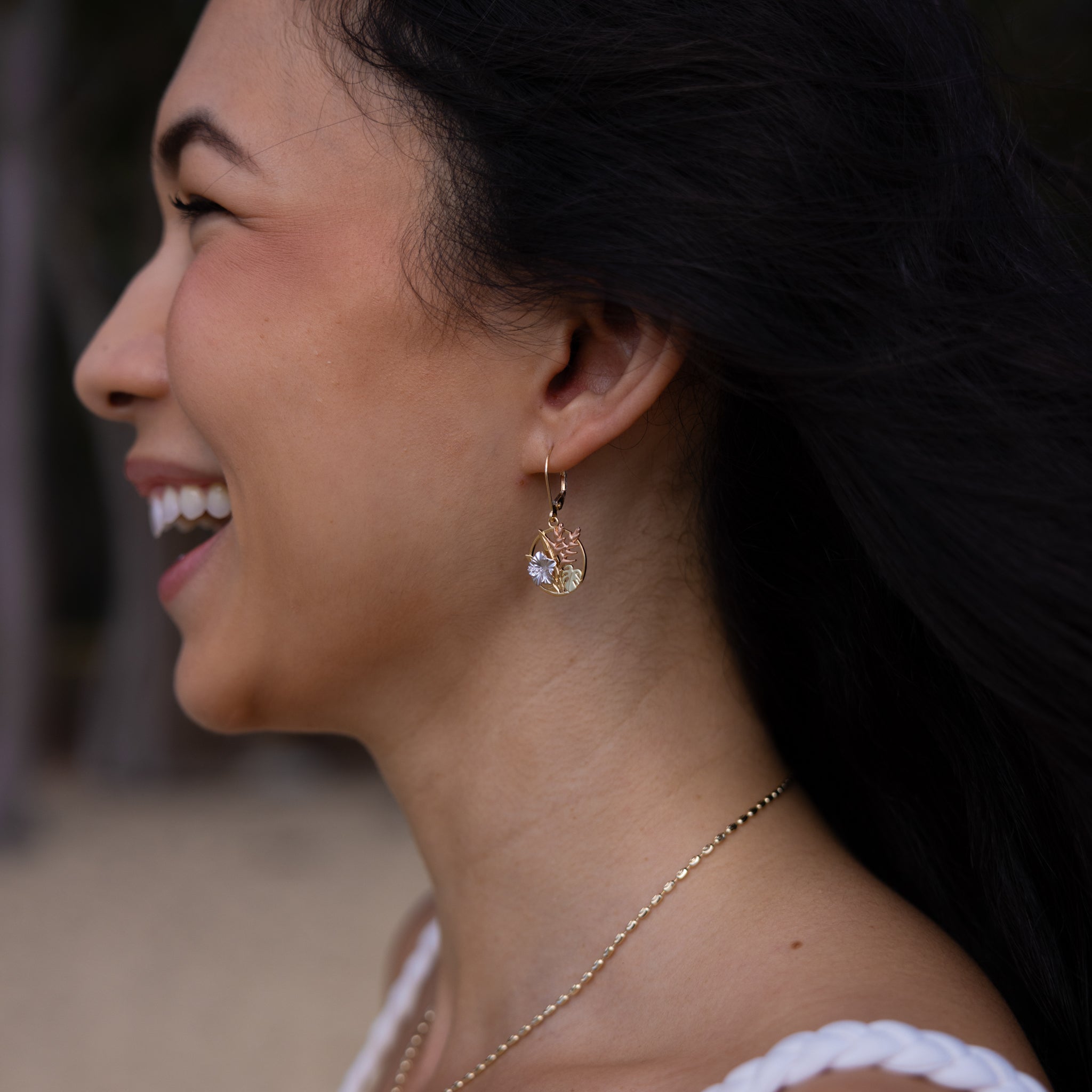 Close up of a woman wearing Hawaiian Gardens Hibiscus Earrings in Four Tone Gold with Diamonds
