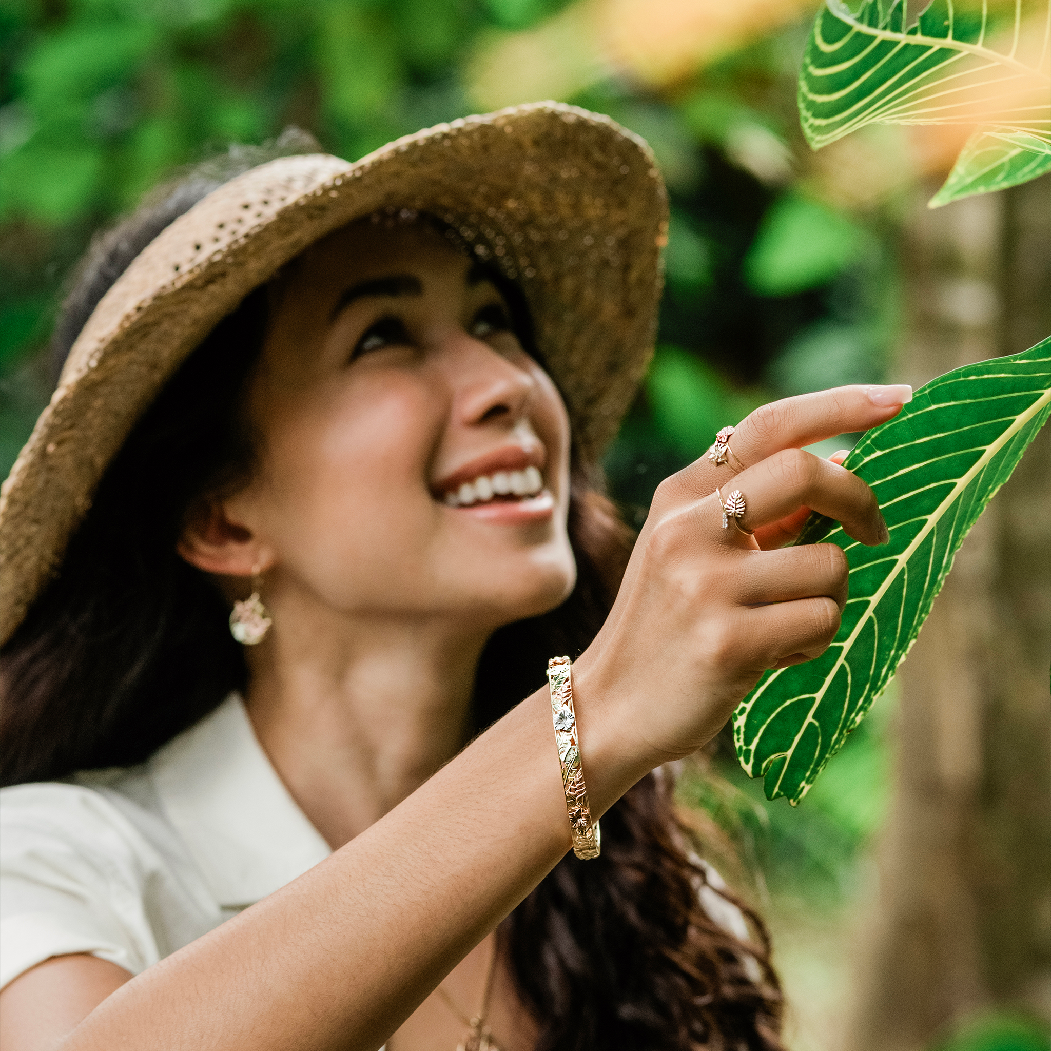 Woman in a tropical garden wearing a Hawaiian Gardens Hibiscus Ring and Bracelet in Gold with Diamonds