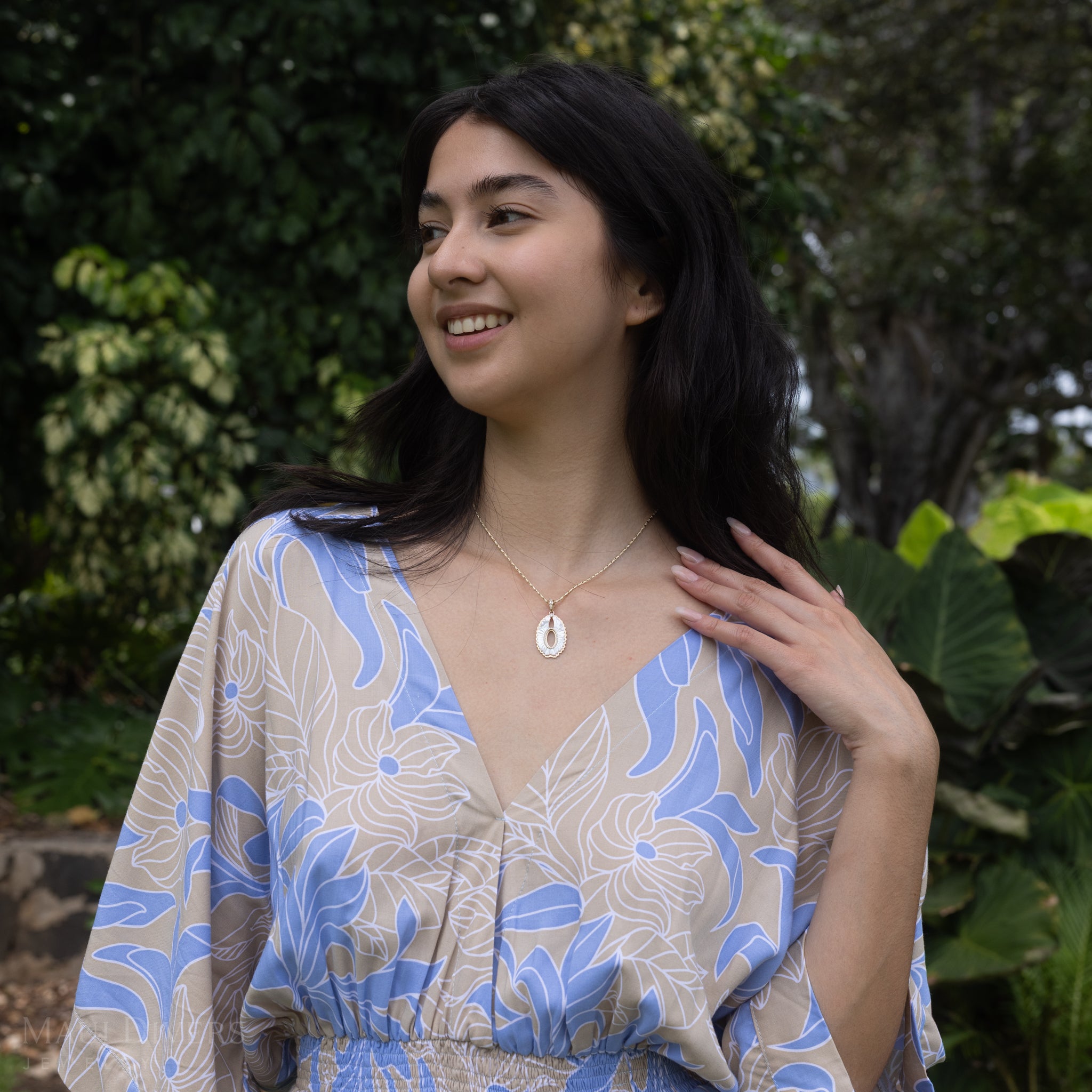 Woman in tropical garden wearing Pueo (Owl) Mother of Pearl Pendant in Gold with Diamonds